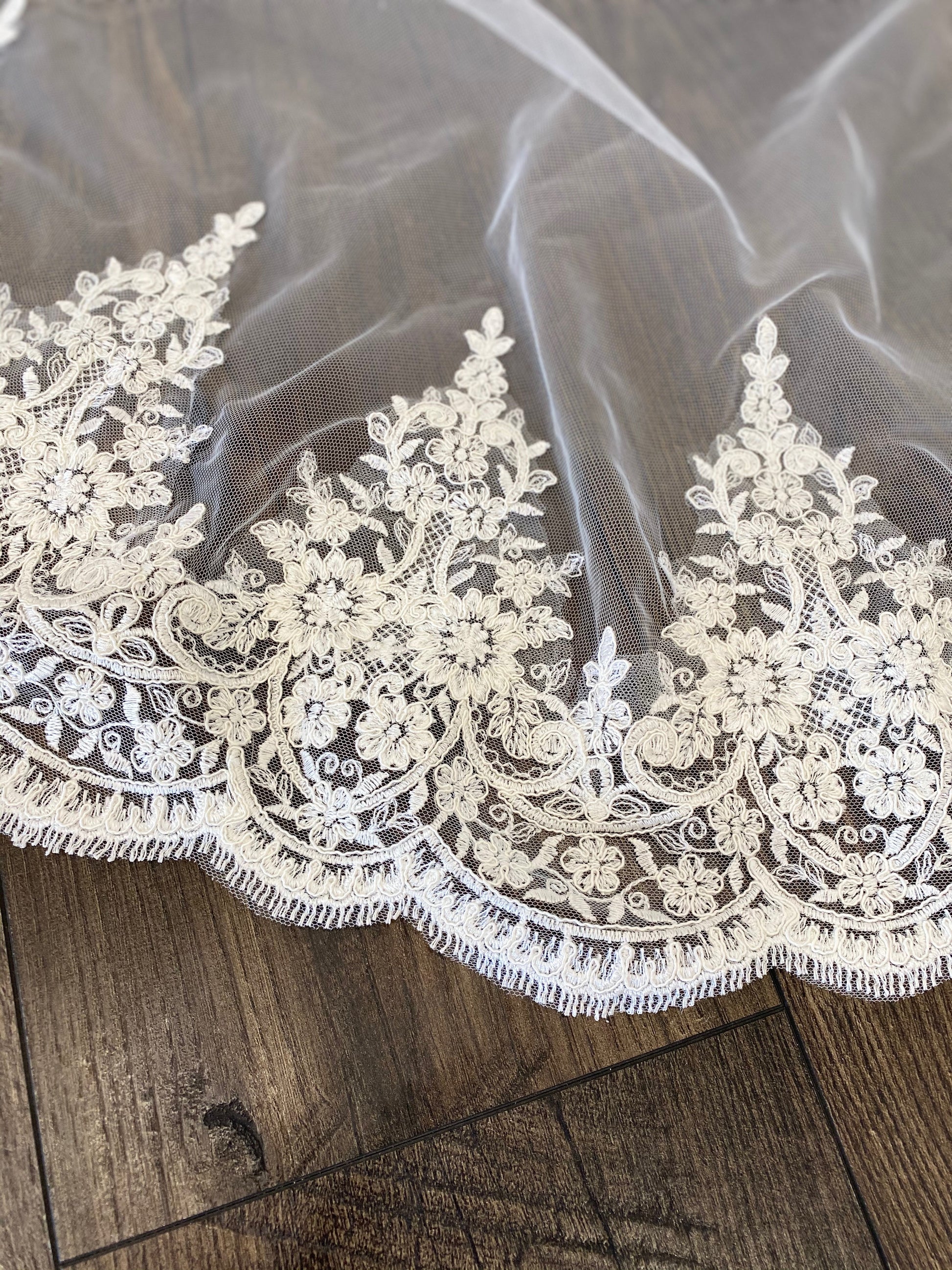 Close-up of the embroidered lace trim on the April veil, highlighting the intricate floral pattern against the pale ivory tulle.