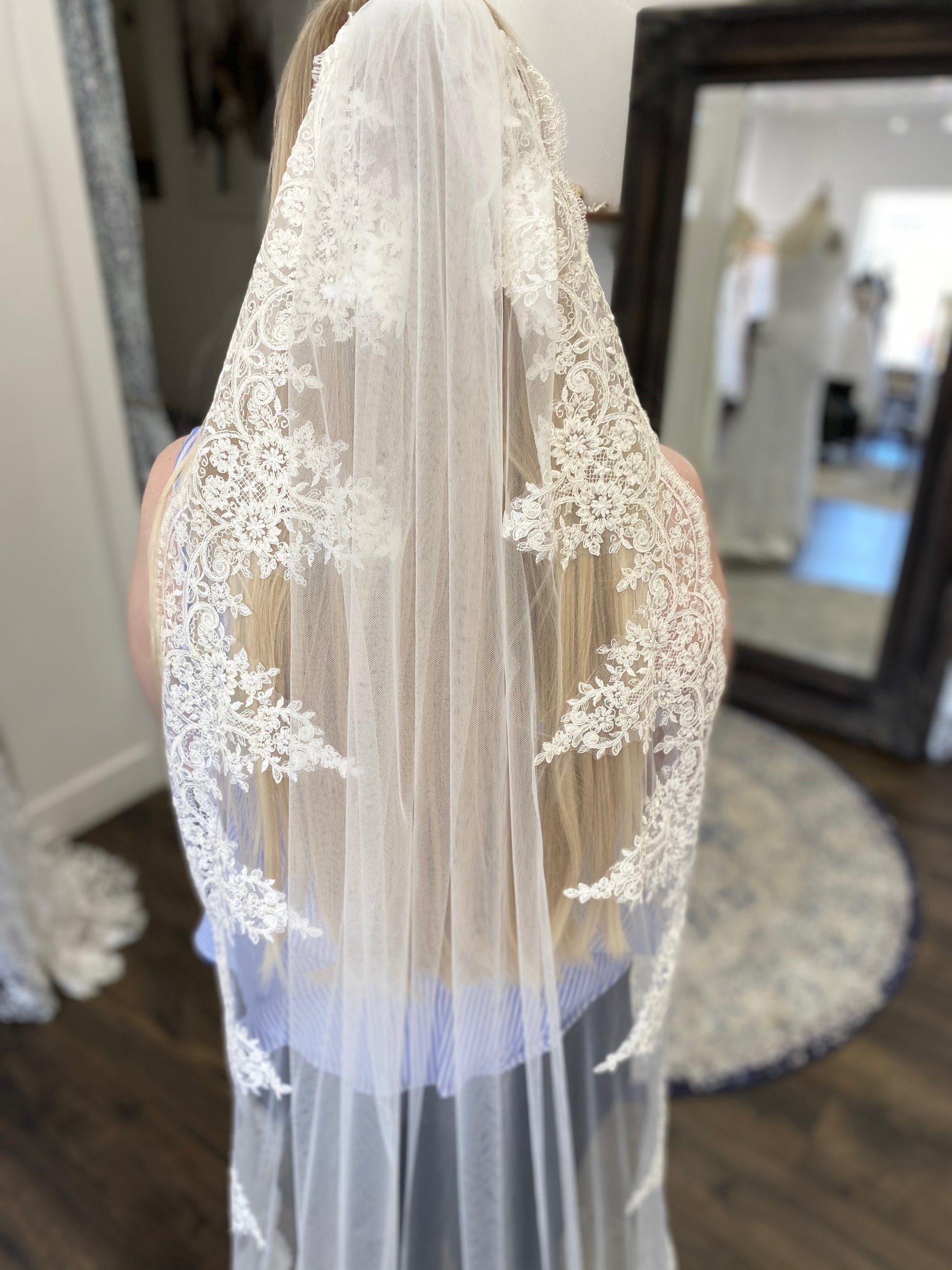 Bride wearing the April veil behind her shoulders, lace trim resting against the side of her back for a soft and graceful silhouette.