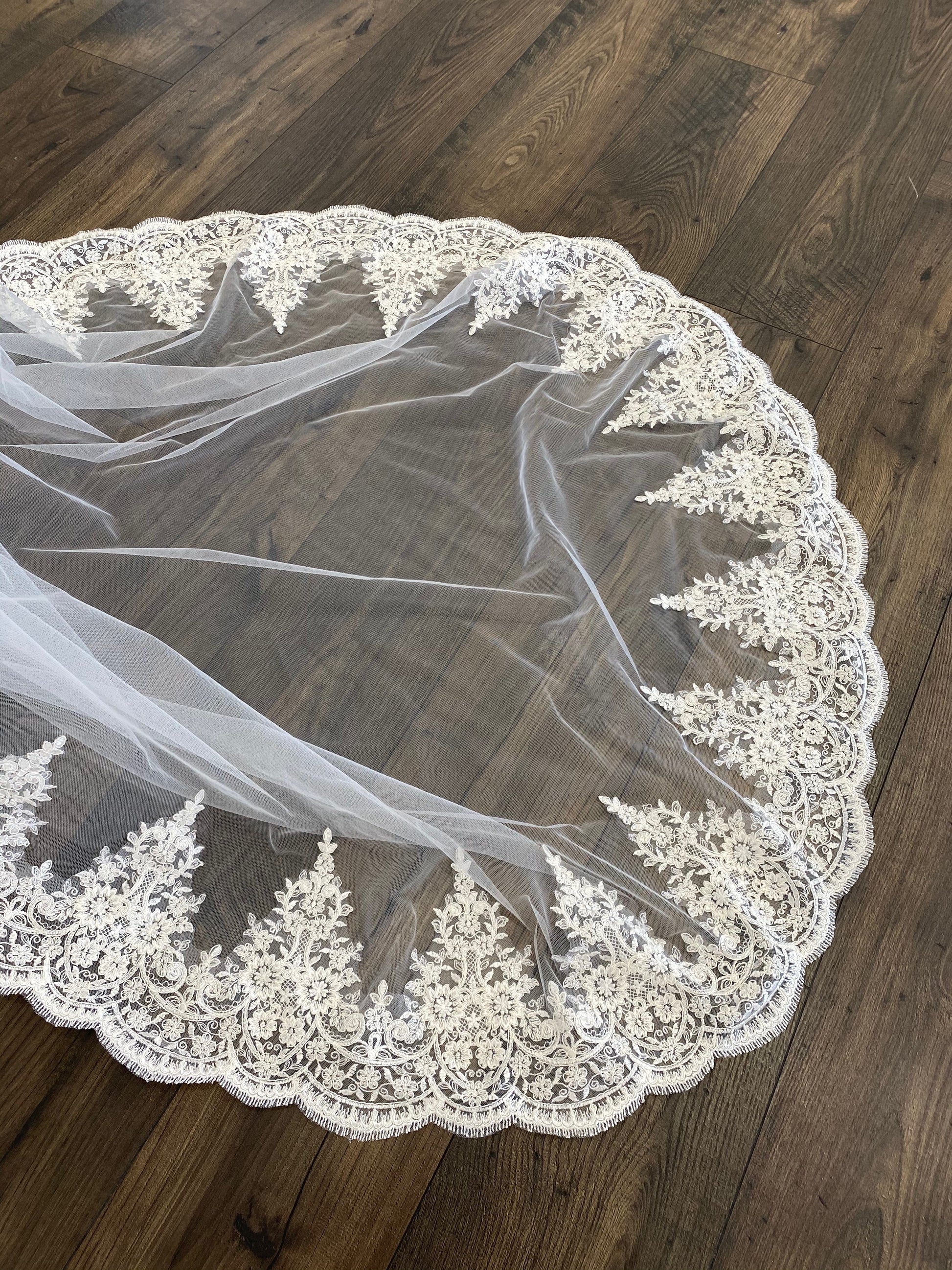 April veil in cathedral length spread out on the floor showing off the curved edge of the veil and lace scalloping.