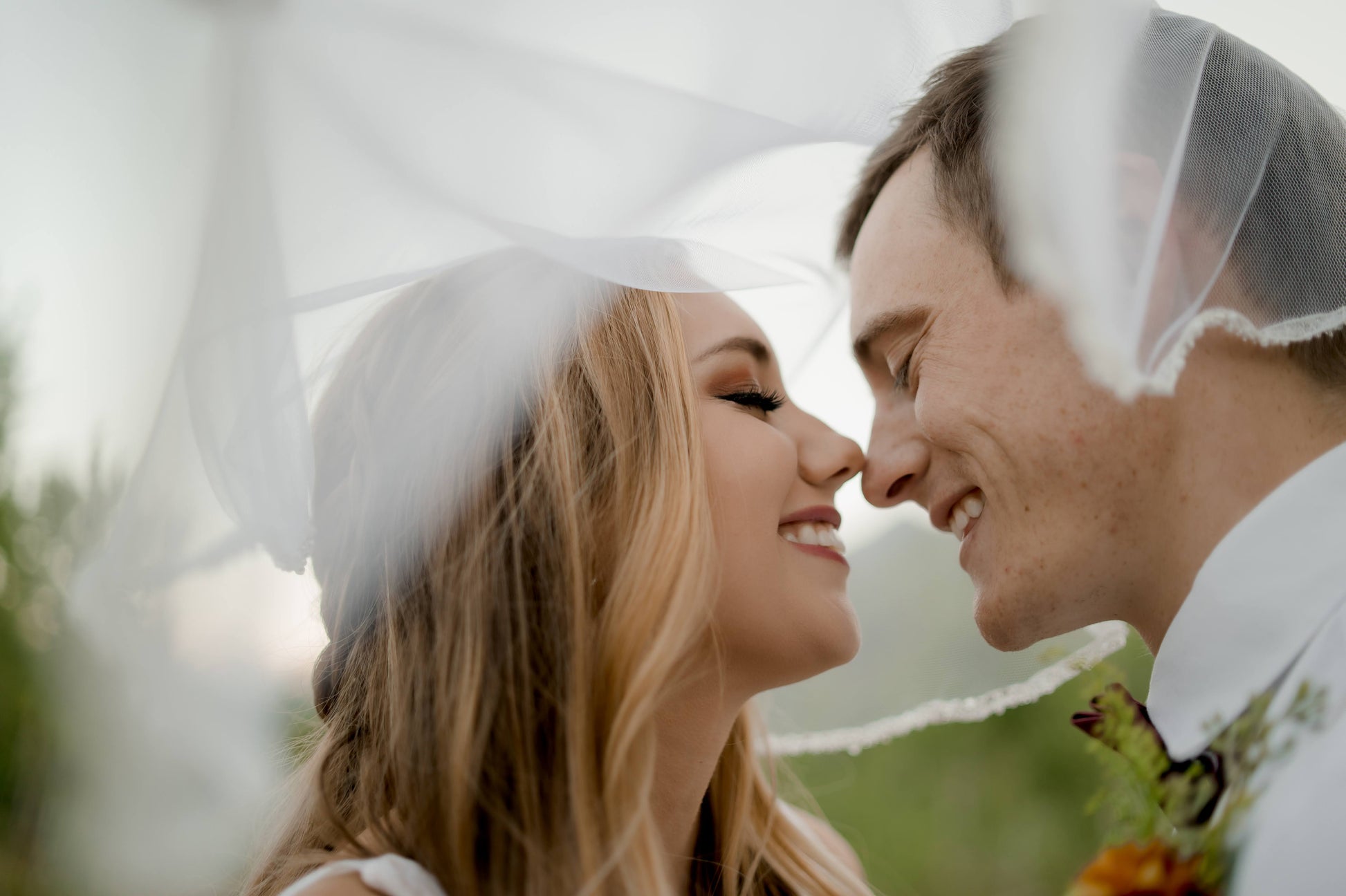 a photo of a couple leaning in for a kiss with the lena veil draped over their heads; the lena bridal veil has a trim all the way around the perimeter.