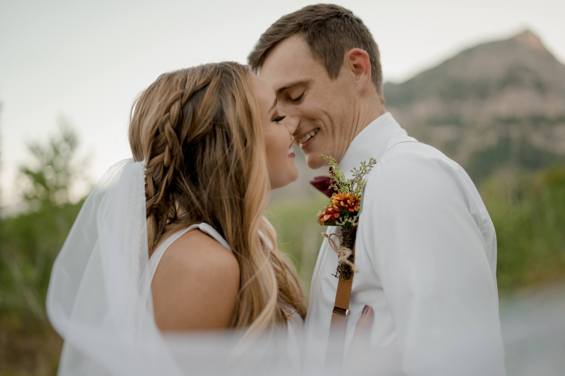 A couple is about to kiss, the bride is wearing the lena veil in fingertip length, the veil is swooping toward the camera like its caught in the wind.