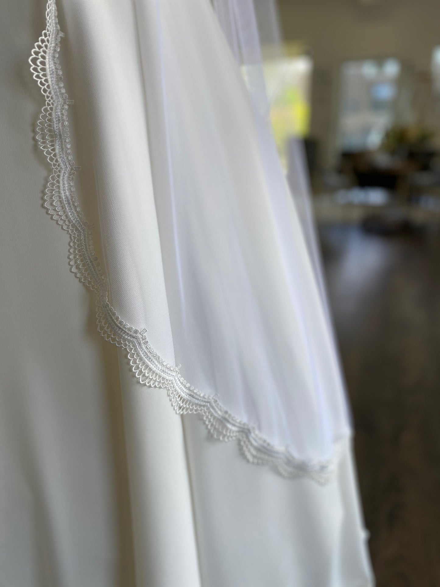 A close up of the curved edge of the brennan bridal veil; the veil is laying against the bottom of the Wendy crepe skirt. The soft tulle base lays close to the body with little volumne.