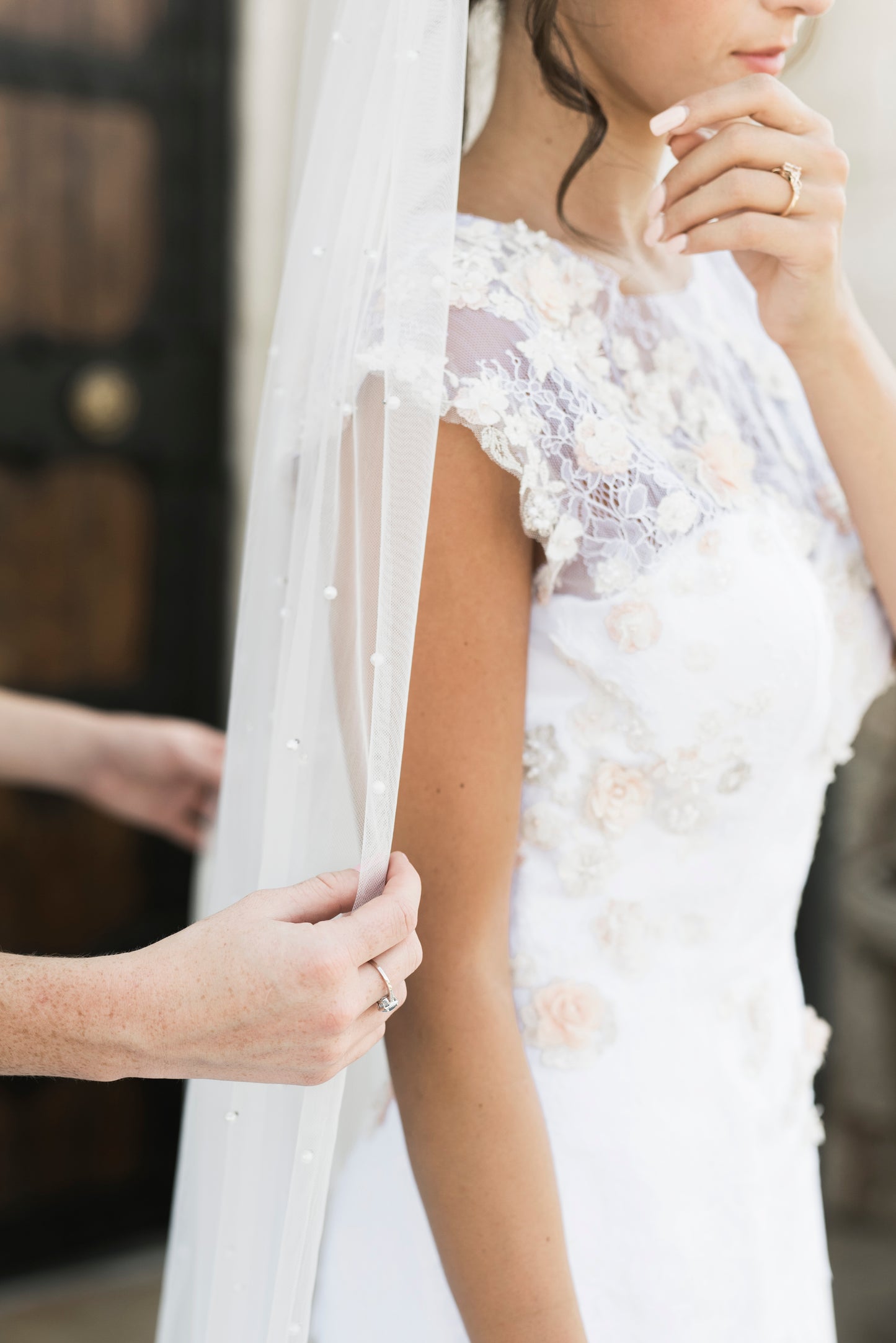 A side angle of the naomi gown styled with the leah veil; the Sculpted crepe mermaid silhouette with lace accents down the bodice are visible.