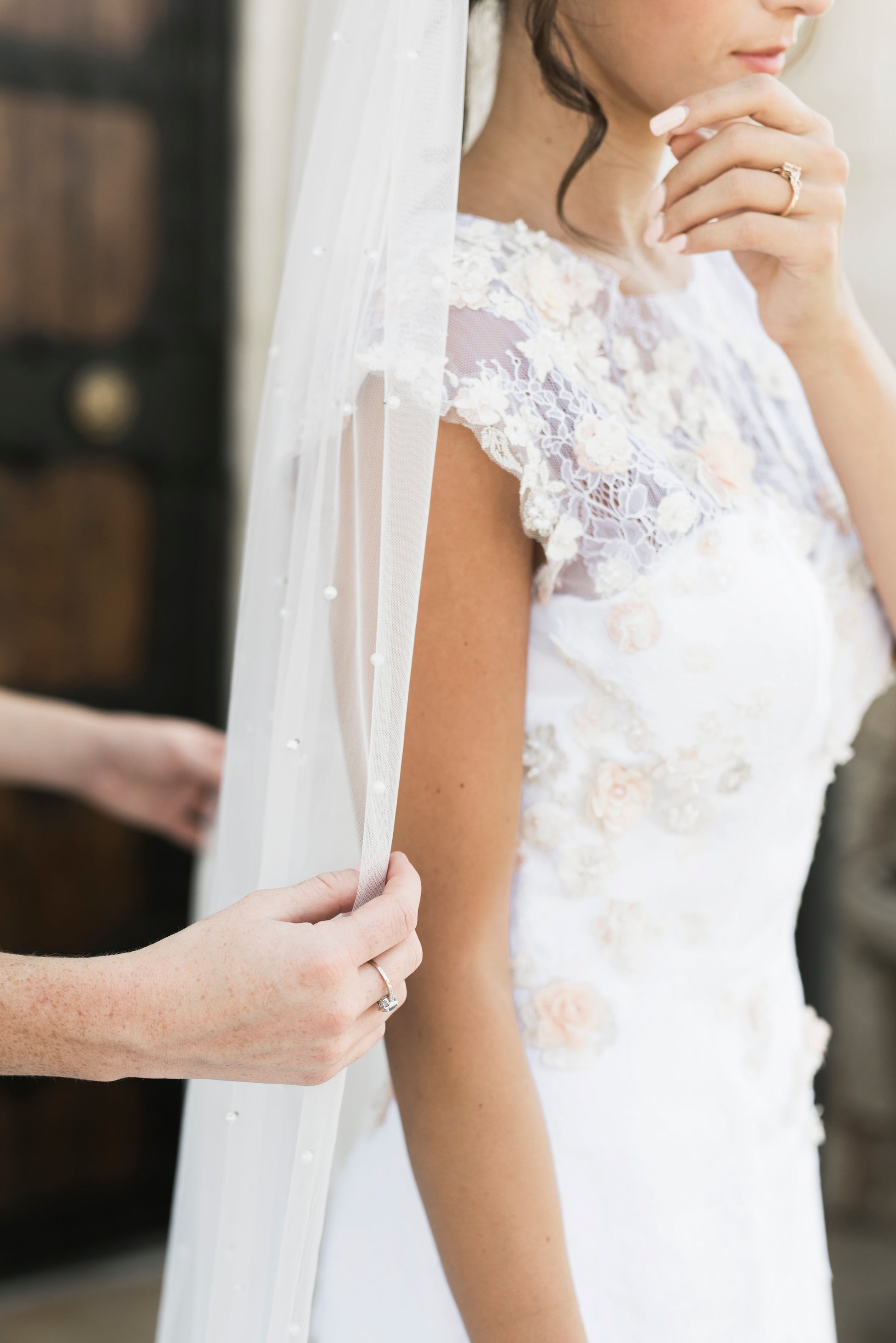 A side angle of the naomi gown styled with the leah veil; the Sculpted crepe mermaid silhouette with lace accents down the bodice are visible.