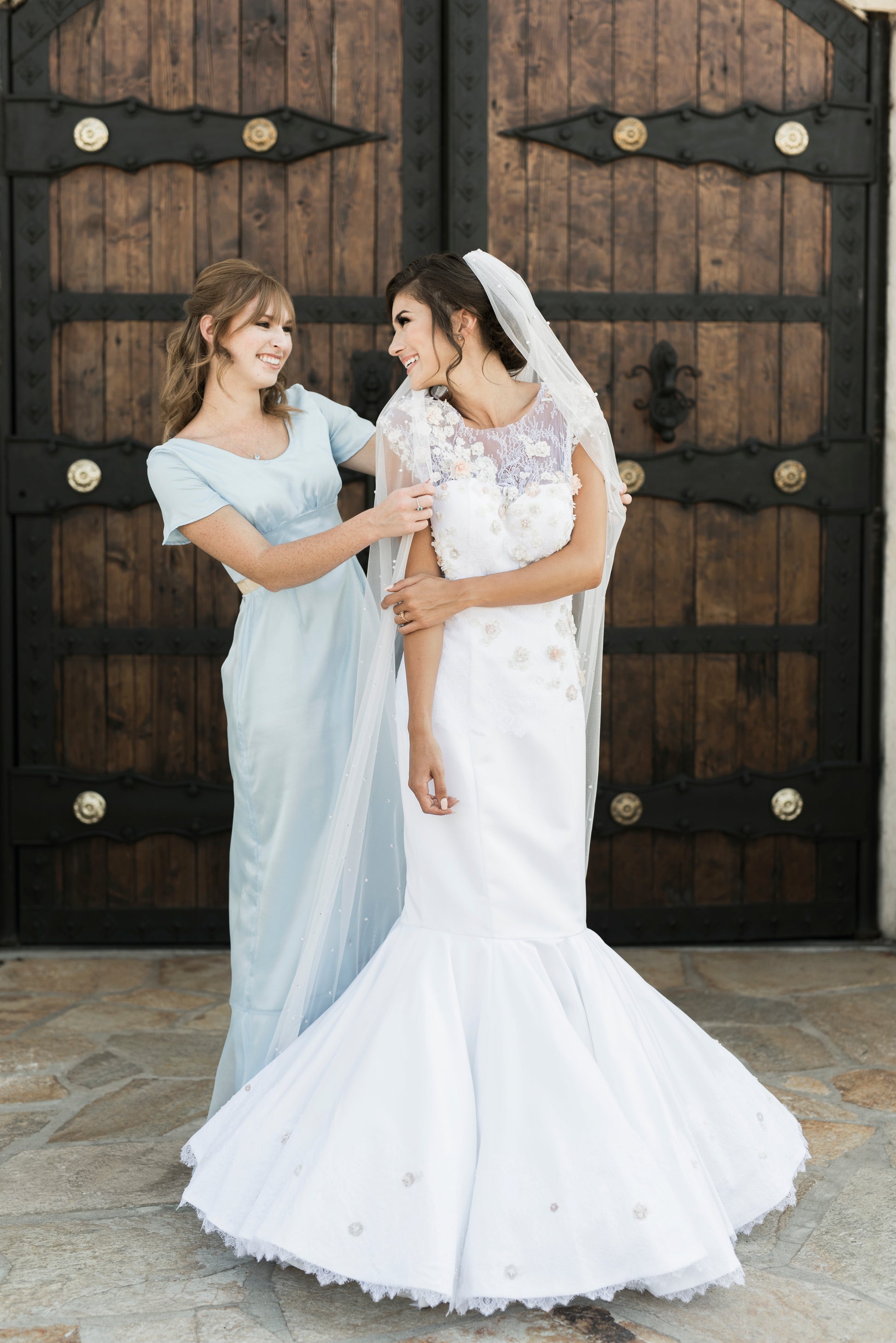 A bride wearing the naomi gown paired with leah; Naomi stretch satin gown with sweetheart neckline and 3D floral lace overlay.