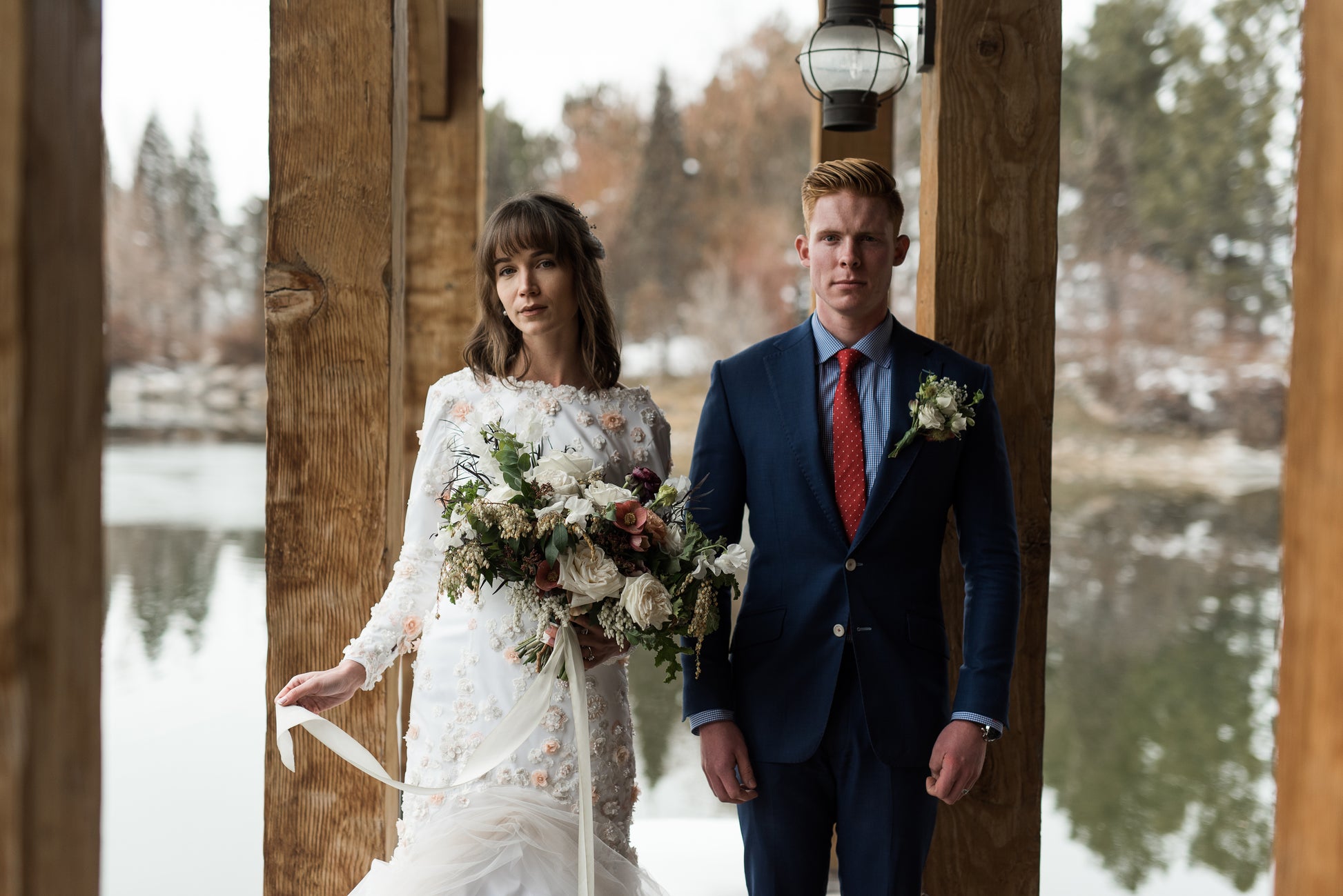 A straight on shot of the Lydia gown on a bride with her groom, showing the wedding gown's boat neckline and 3D floral lace.