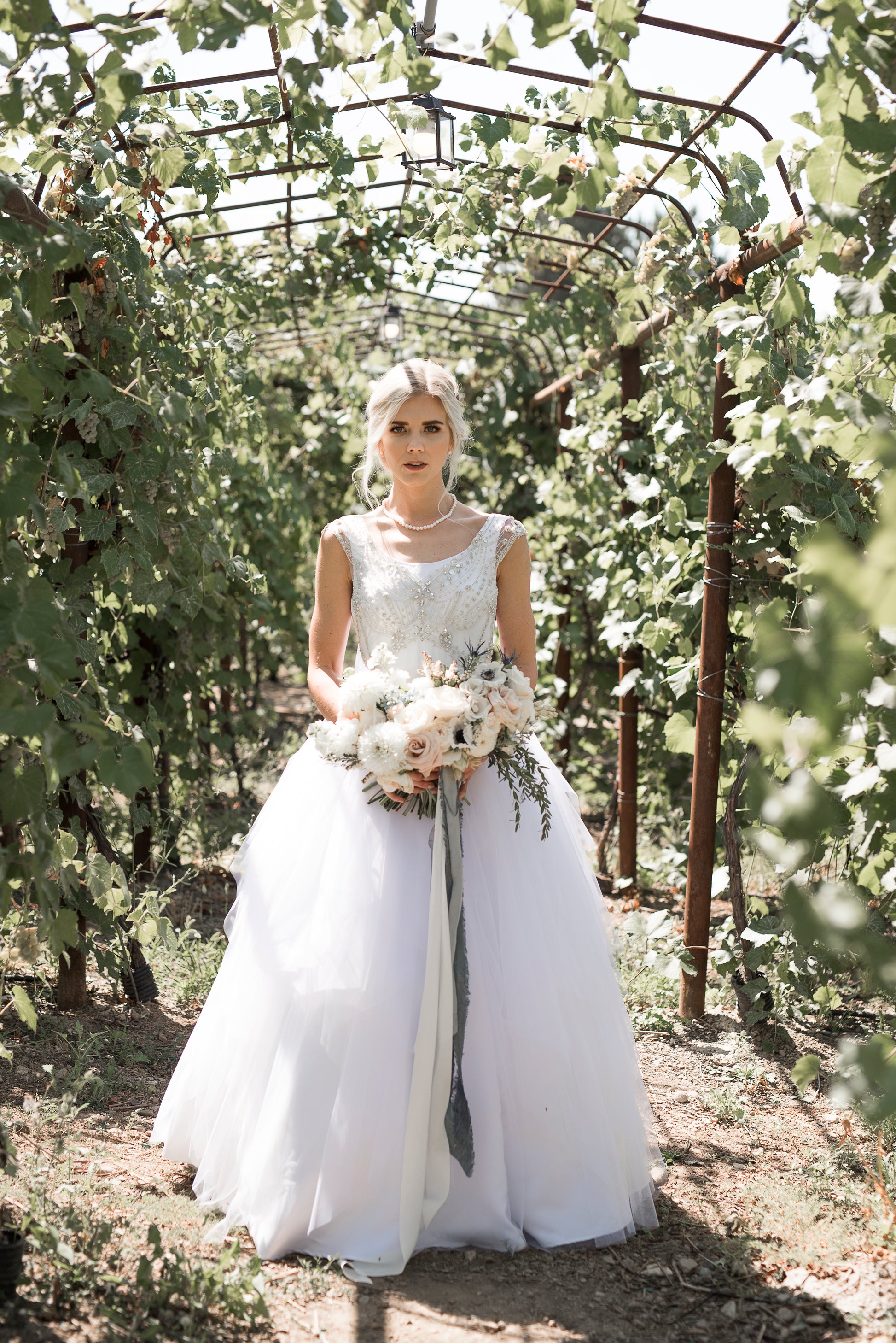 Bride stands in an orchard, the Georgia gown glowing in daylight, rhinestones catching the light across the bodice.