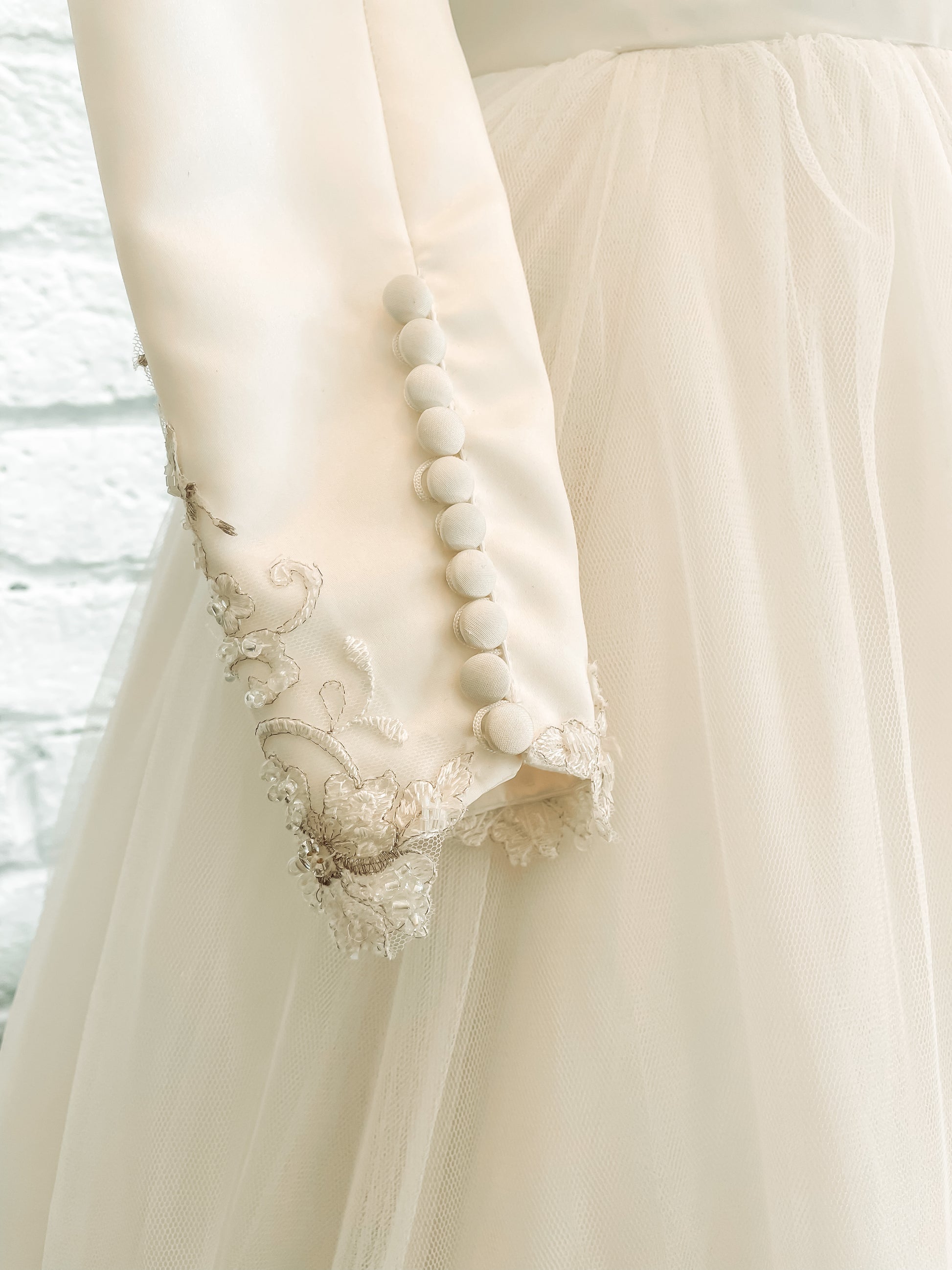 Detail shot of Ava gown's inside wrist long satin sleeve ending in delicate lace  with satin buttons.