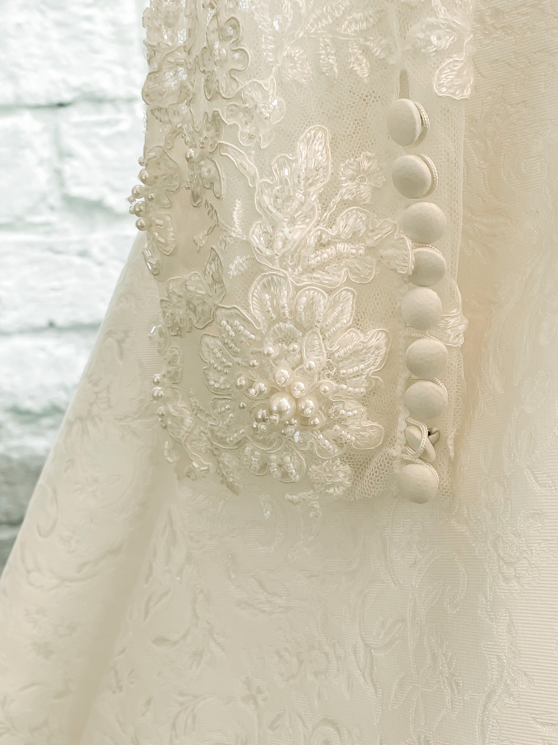 Close-up of lower sleeve lace detail and satin covered buttons at the wrist.