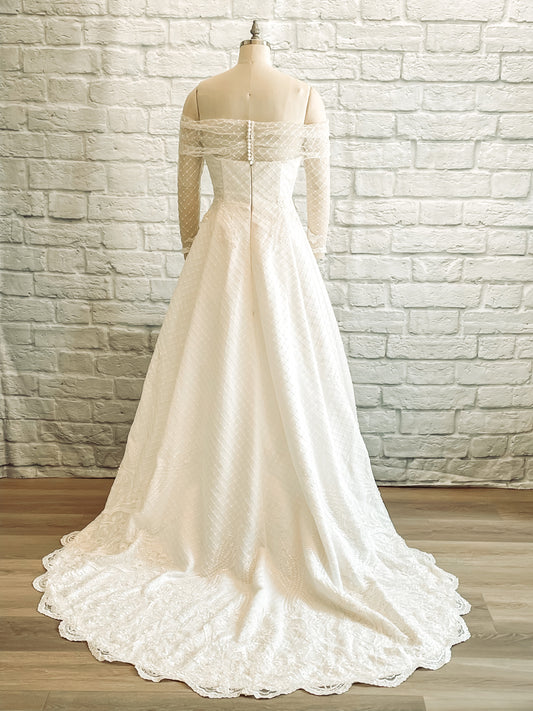 The full back view of the Virginia wedding gown, shown on a mannequin; featuring the covered buttons and sweeping 24-inch lace train.