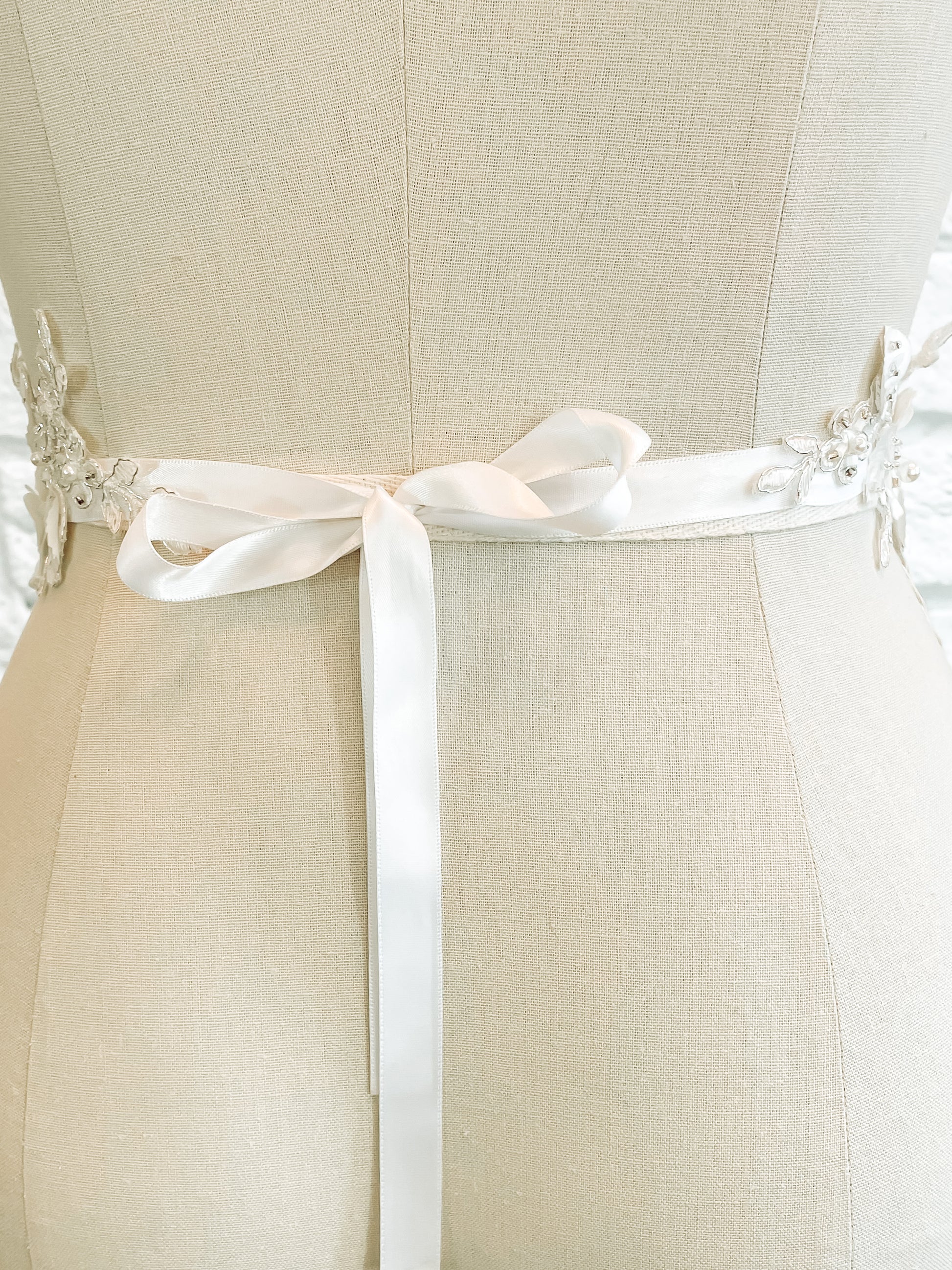 A back photo of the Meghan belt on a mannequin this romantic and whimsical bridal accessory has a ribbon tie with 12" long ties.