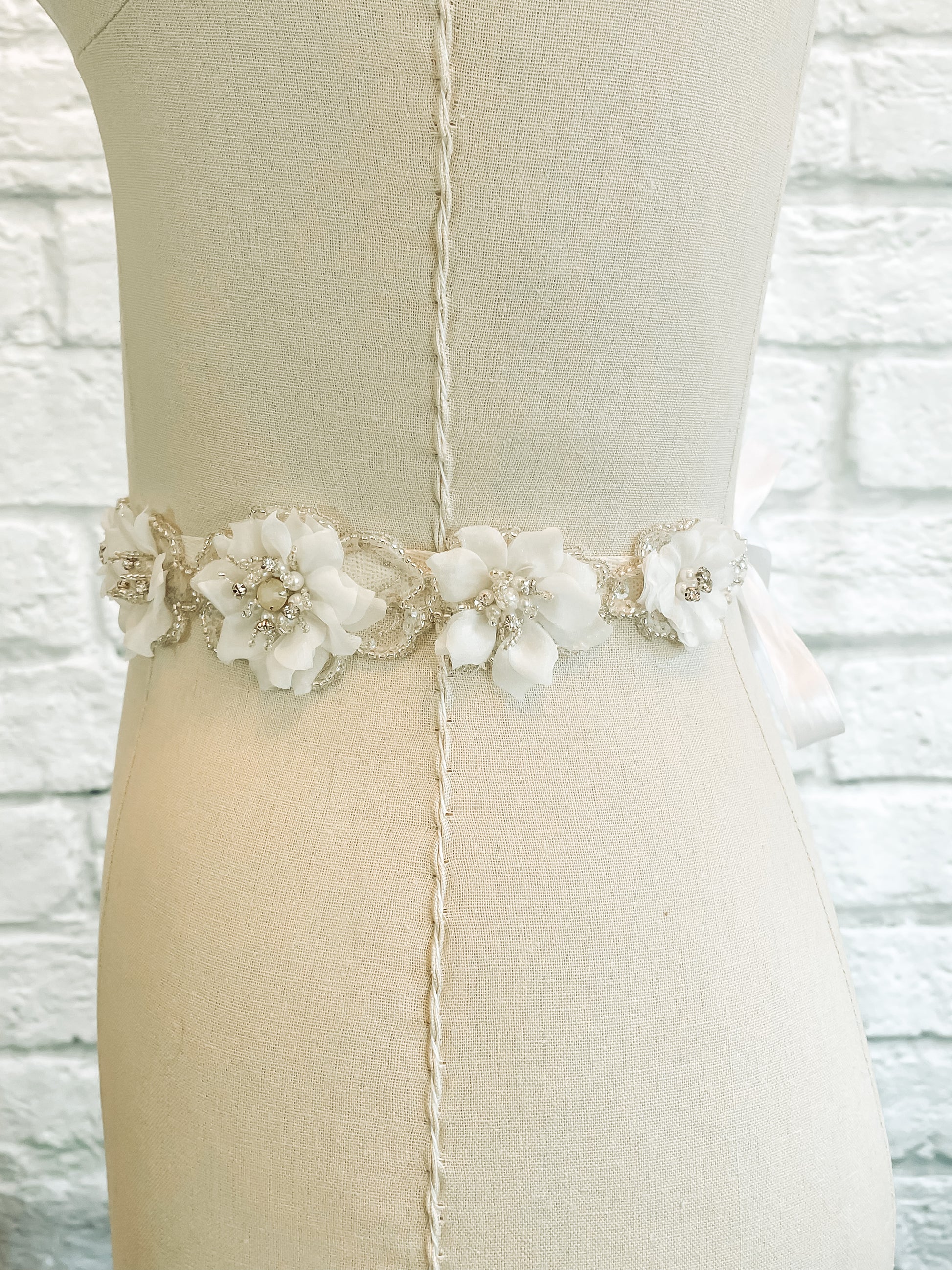 A side view of the Heidi bridal belt on a mannequin; the floral bridal belt showing the side section of the 24-inch floral motif and ribbon ties.