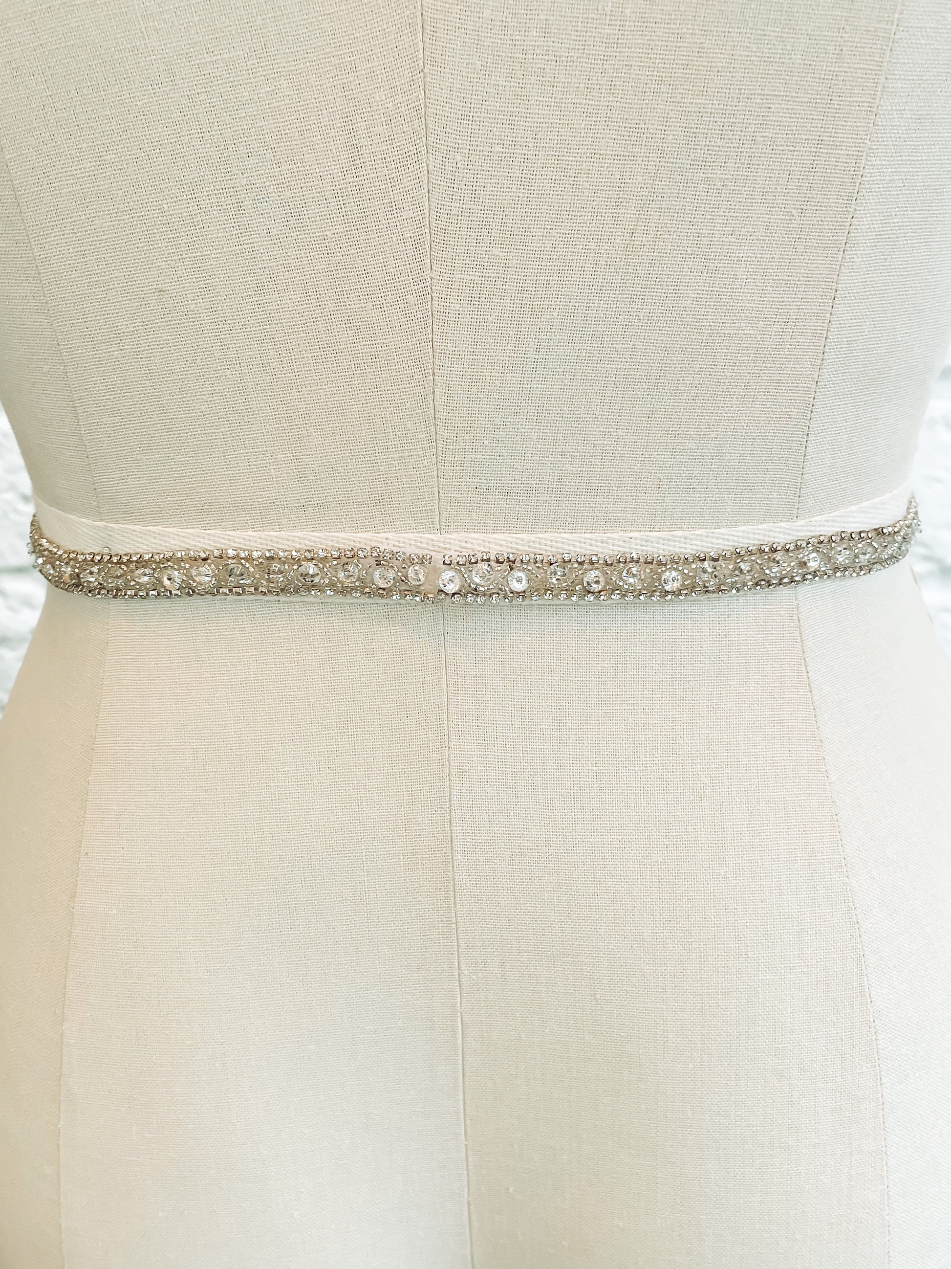 The back of the kelly belt on a mannequin;  half-inch Kelly bridal belt showing intricate bead and rhinestone pattern with the seamless hidden snap closure.