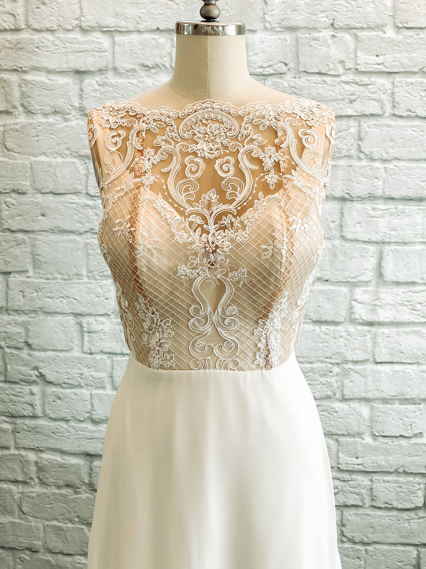 A up close shot of the front Winifred; Pale ivory lace on nude tullé back ground with a mock neck cut and scallop detail.
