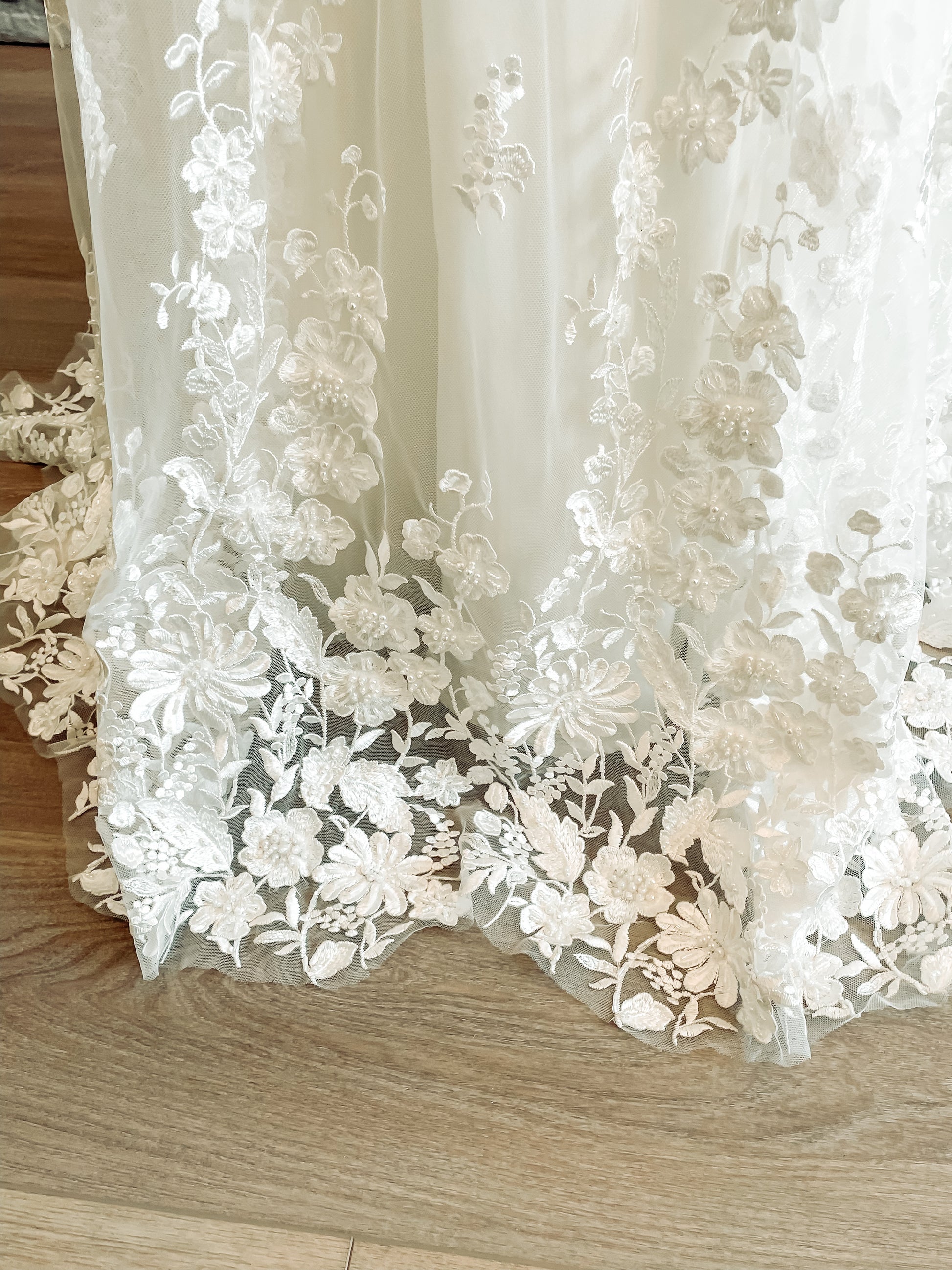 A close up of the hem of the wilhelmina gown, with the natural floral scalloping and beaded lace.