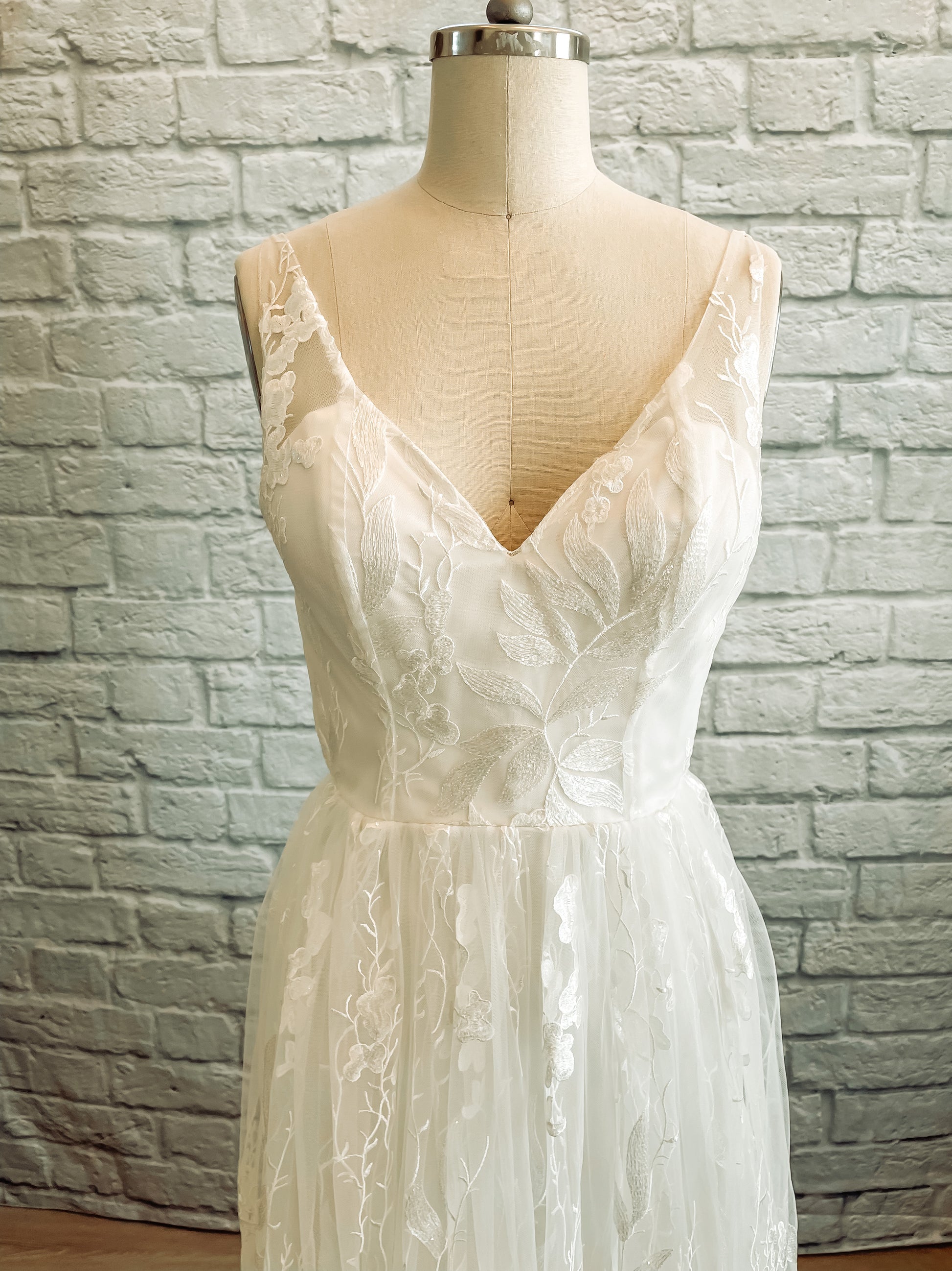 Close up of the front bodice of the Rosie Wedding gown on a mannequin; the Strapless satin sweetheart bodice beneath lace overlay is the focus.