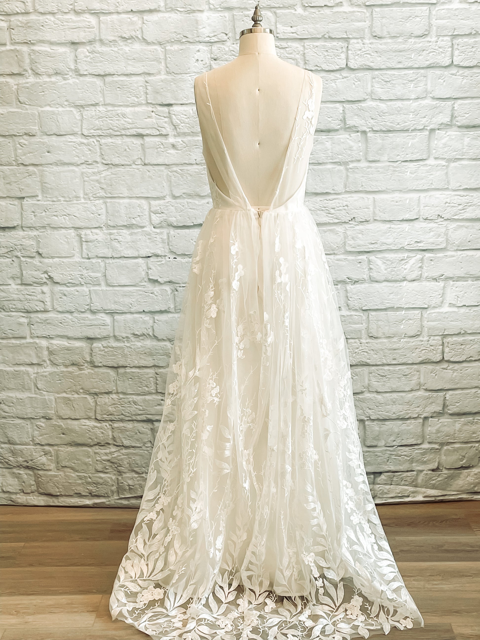 Full back view of the Rosie wedding gown on a mannequin with a Lace-only back bodice, sequin detailing and delicate train.