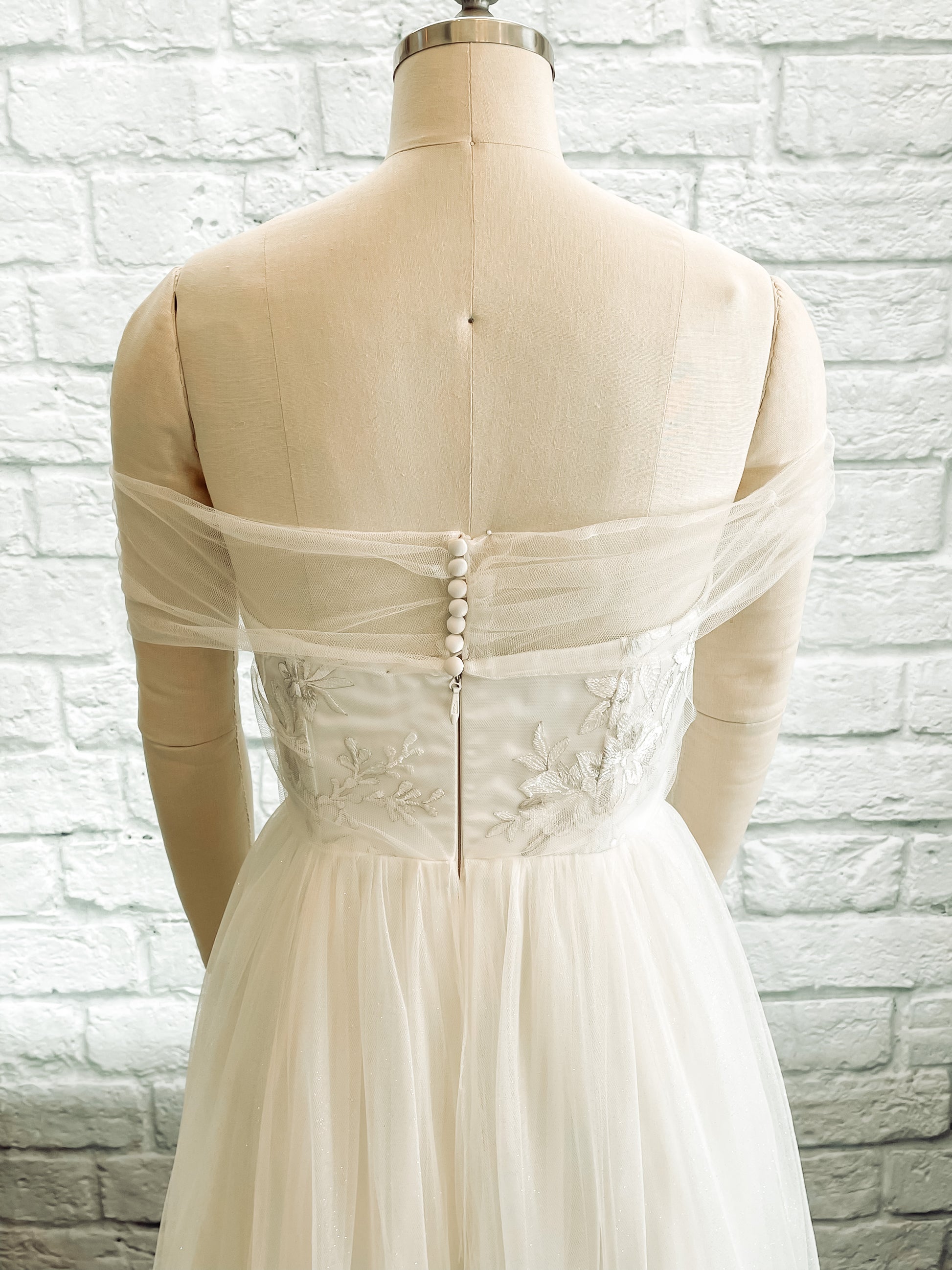 Back bodie view of the penelope gown with the silver ivory lace, satin covered bridal buttons, and tulle skirt.