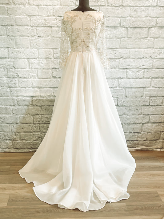 The theodora wedding dress is on a mannequin showing the full length back view; a High boat neck bodice and organza train measuring 17".