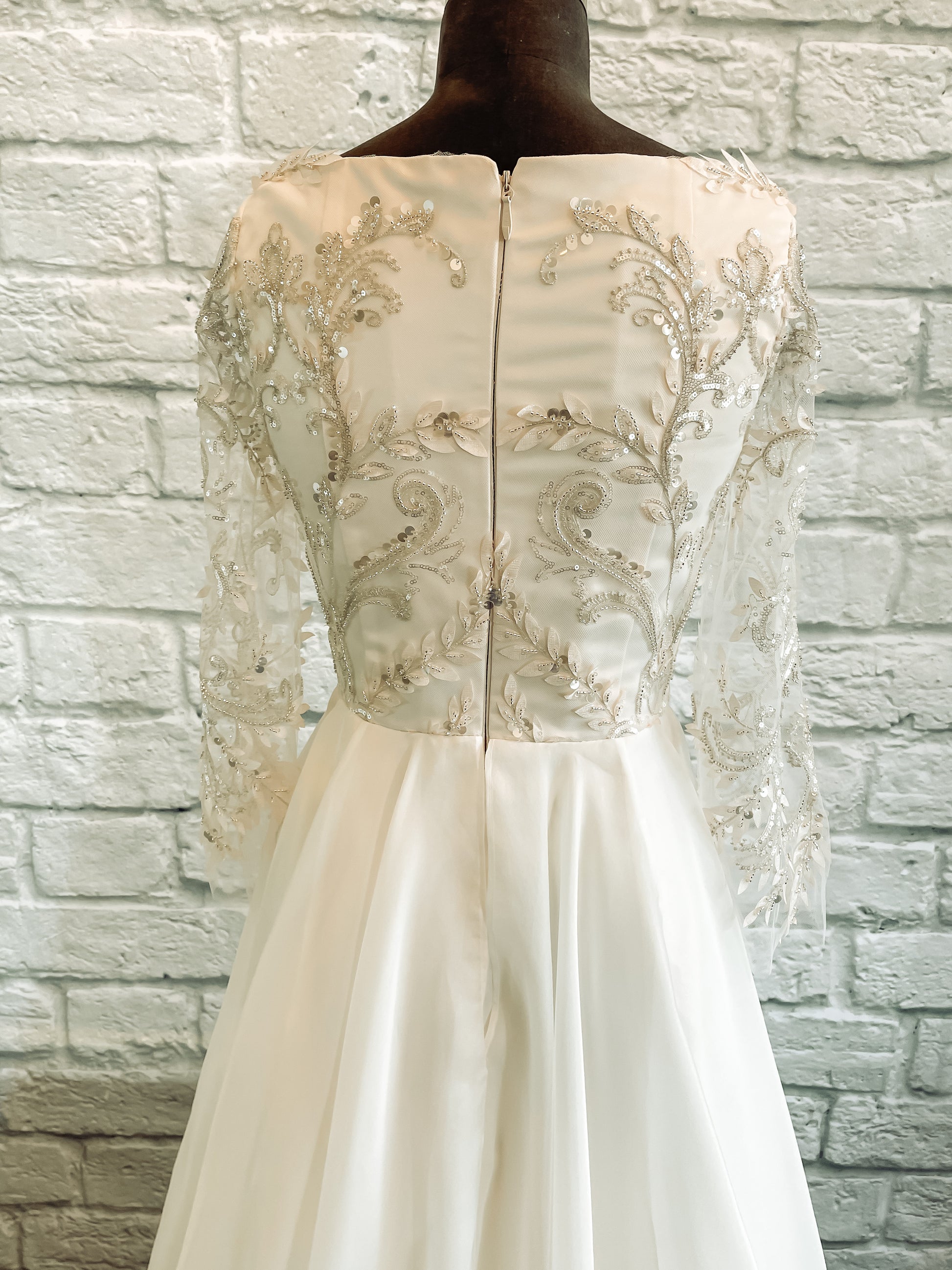 The bodice of the theodora gown is shown here on a mannequin in a close up of the back; the 3D embroidered leaves and silver sequin lace pattern is the focal point.
