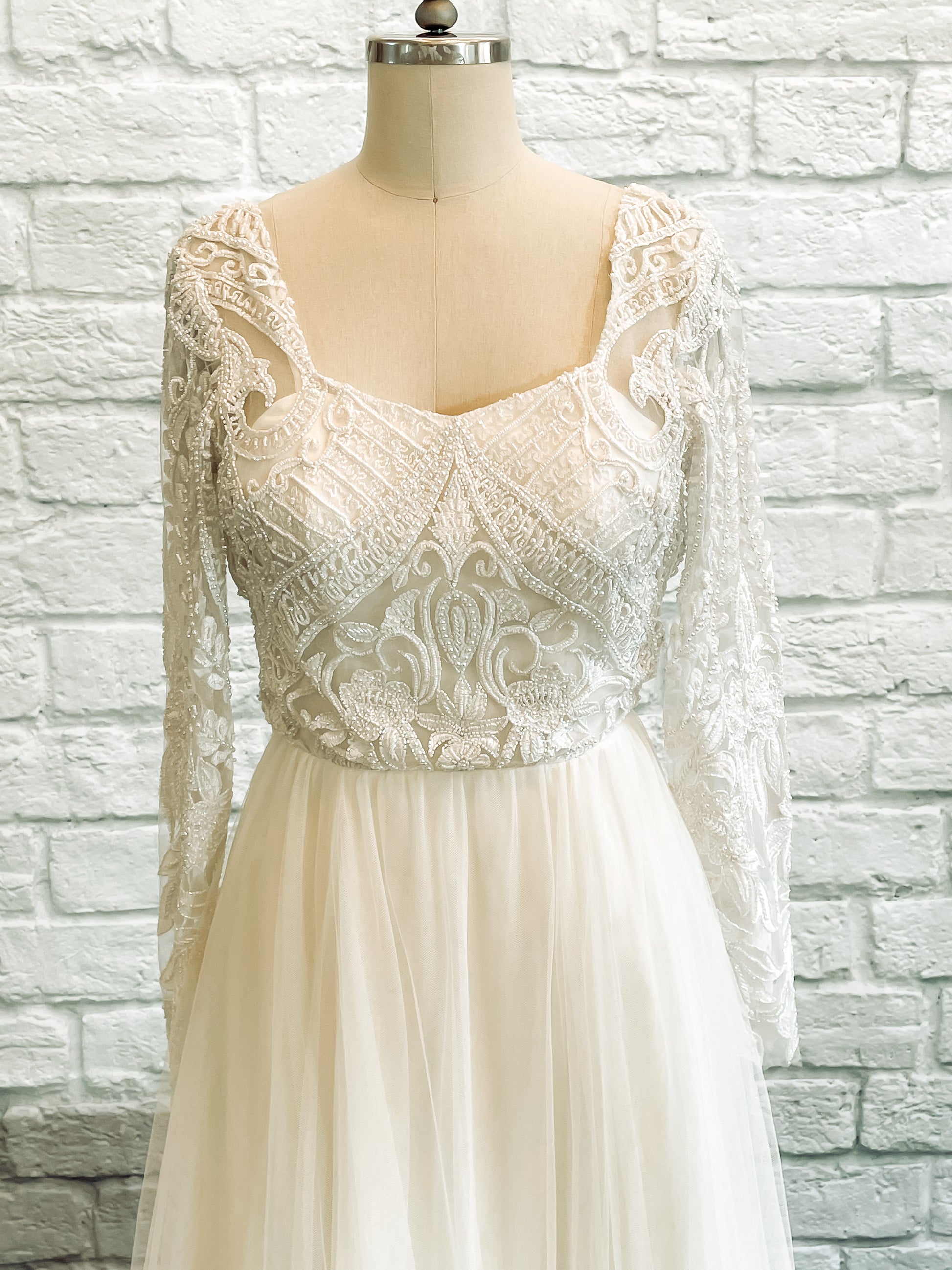 Detail of heavily beaded lace overlay with botanical motifs and sleeve scallop