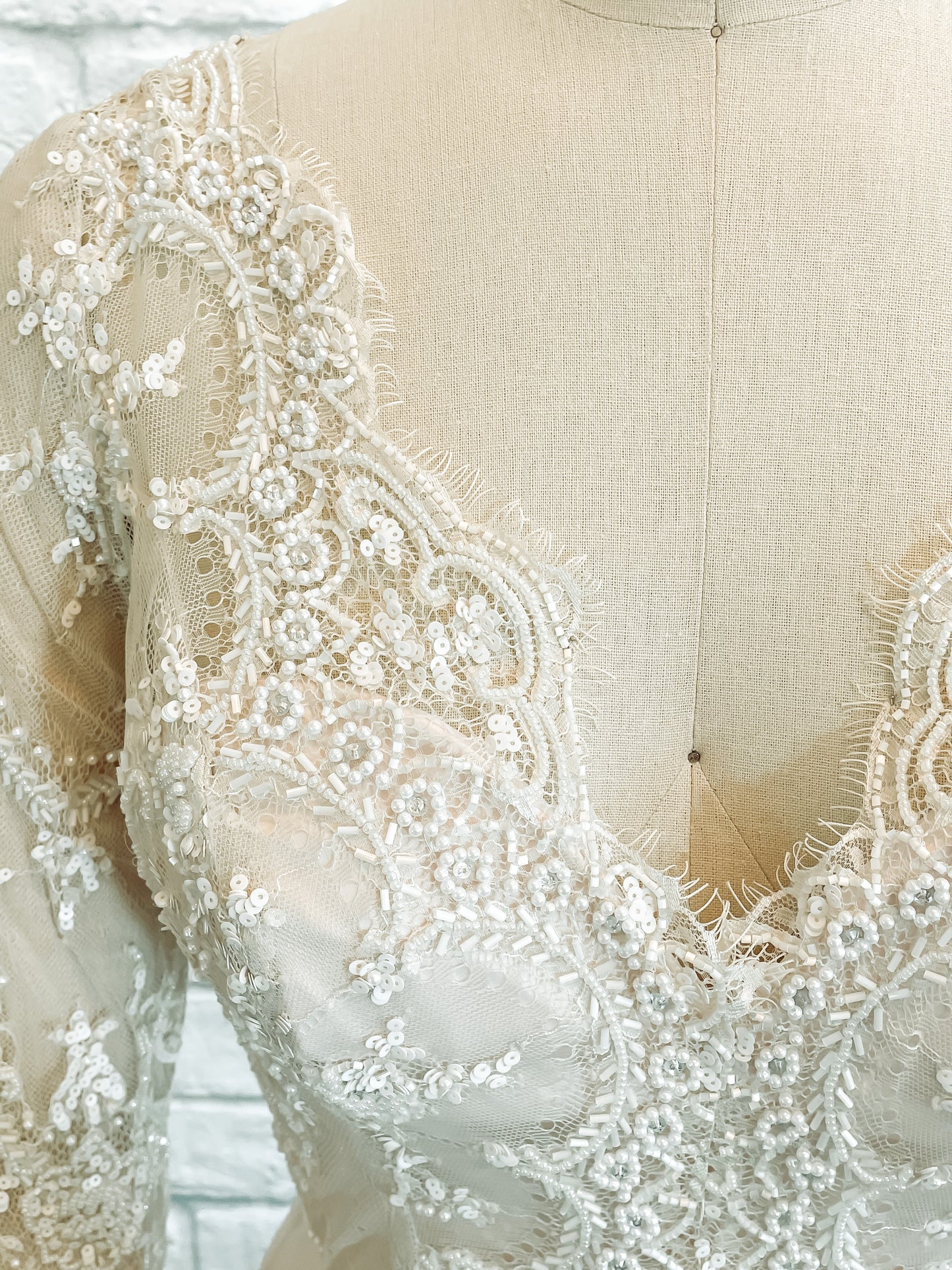 Close-up of lace bodice on mannequin, highlighting vintage-inspired beaded lace, scalloped neckline, and sweetheart satin base.