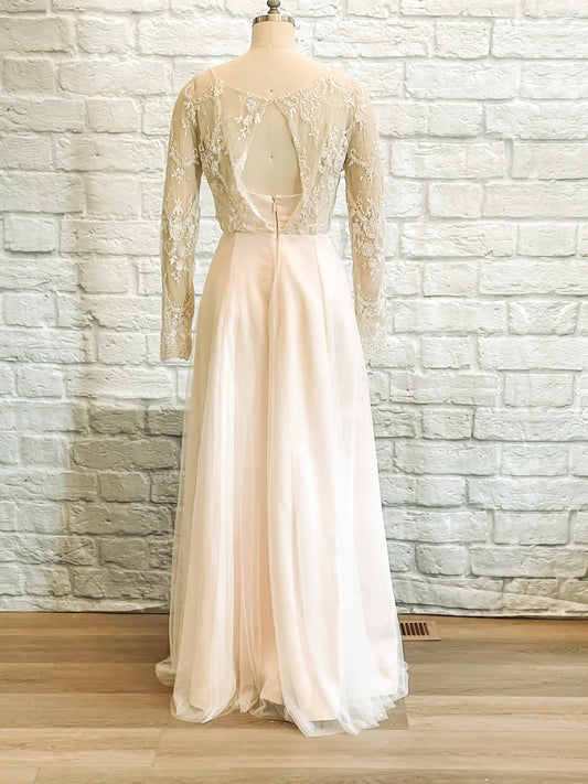 Back view of mannequin wearing Eivissa gown, showcasing fitted lace sleeve, waist seam, keyhole back, and gentle A-line silhouette.