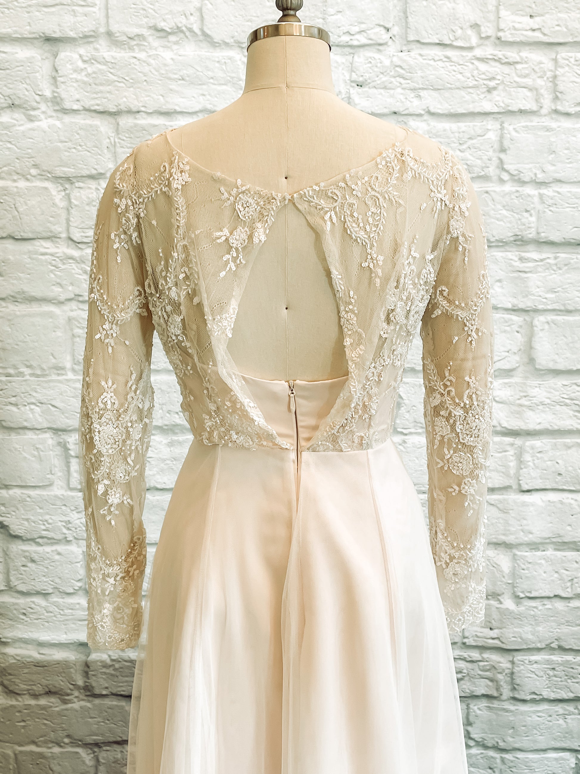 Mannequin turned away, revealing the boat neck lace back and soft closure at the top of the bodice.