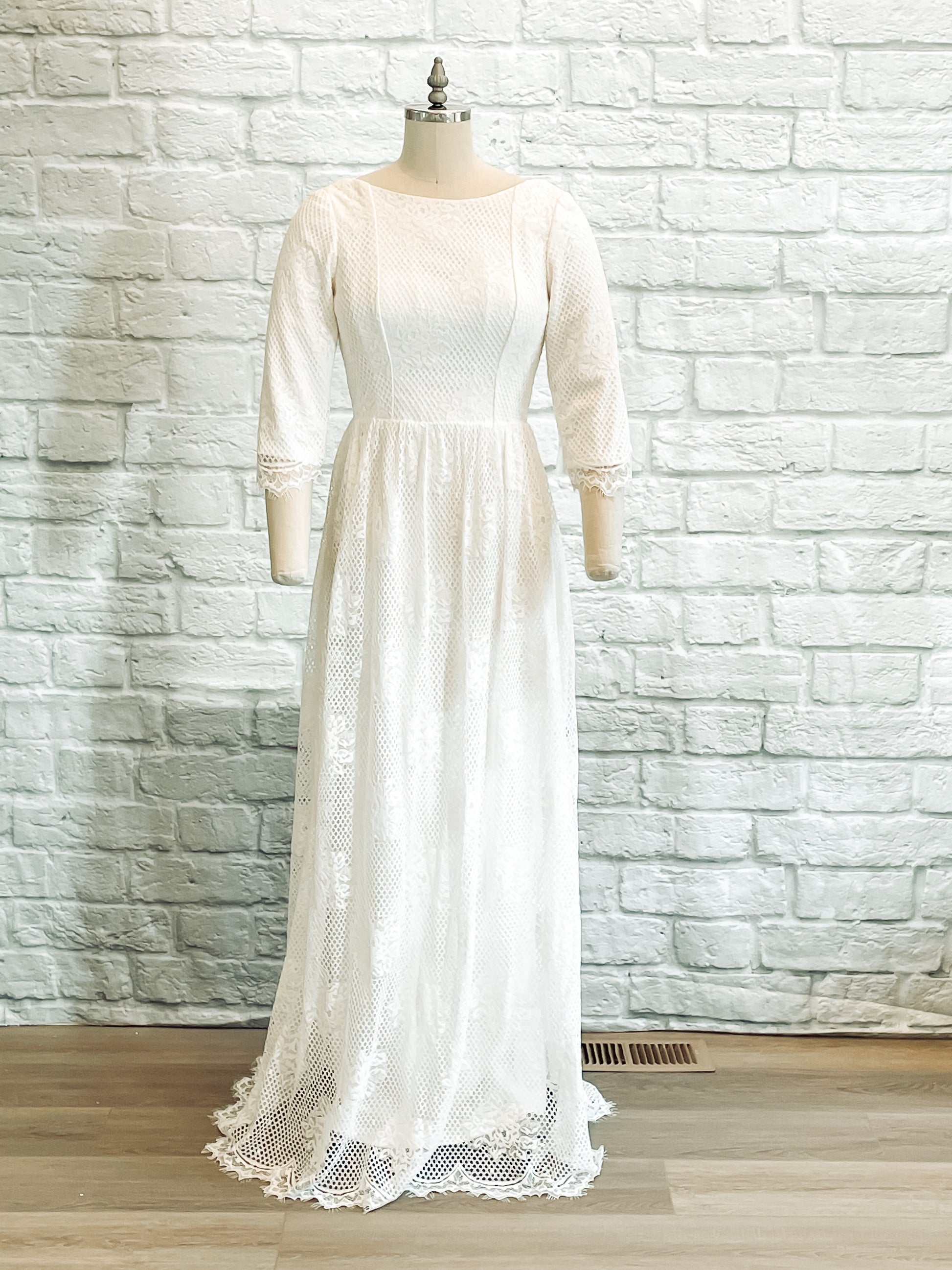 Avabelle wedding gown displayed on a mannequin, featuring a boat neckline, fitted lace bodice, and modified A-line silhouette with soft lace overlay.