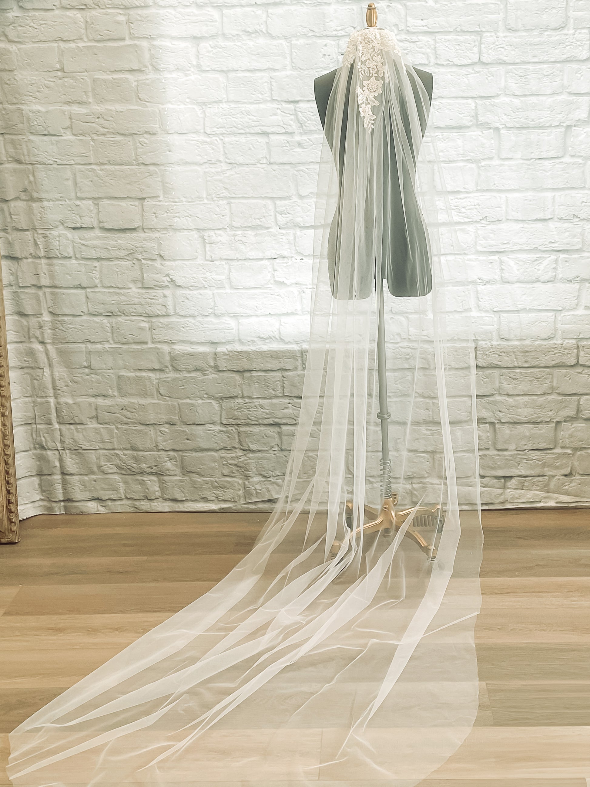 A full length photo of the romantic tulle veil sharon veil displayed on a mannequin in a chapel length with floral beaded lace.