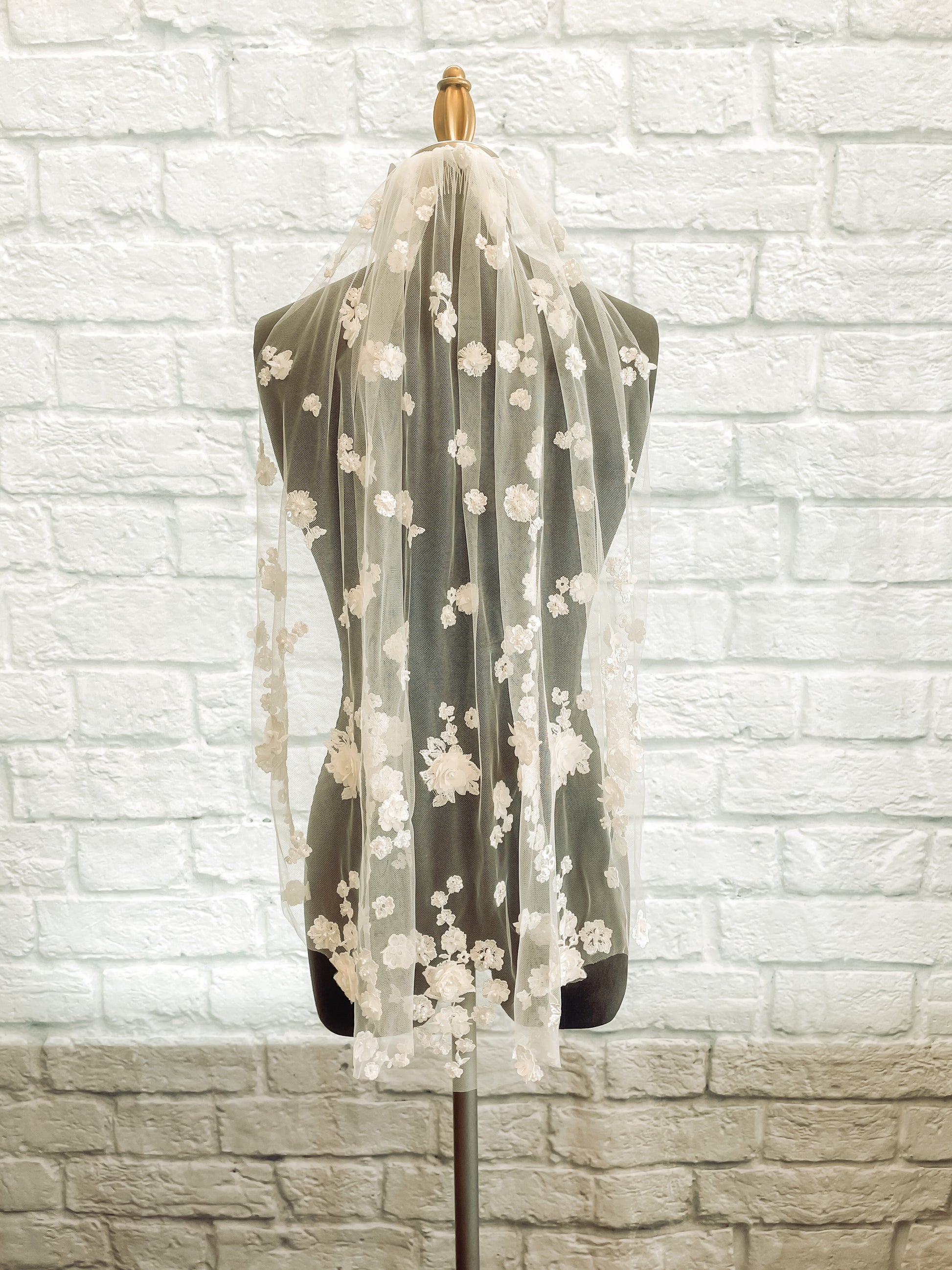 A full length veil of the Tiana veil in a fingertip length and pale ivory color; it has pearls and sequin details.