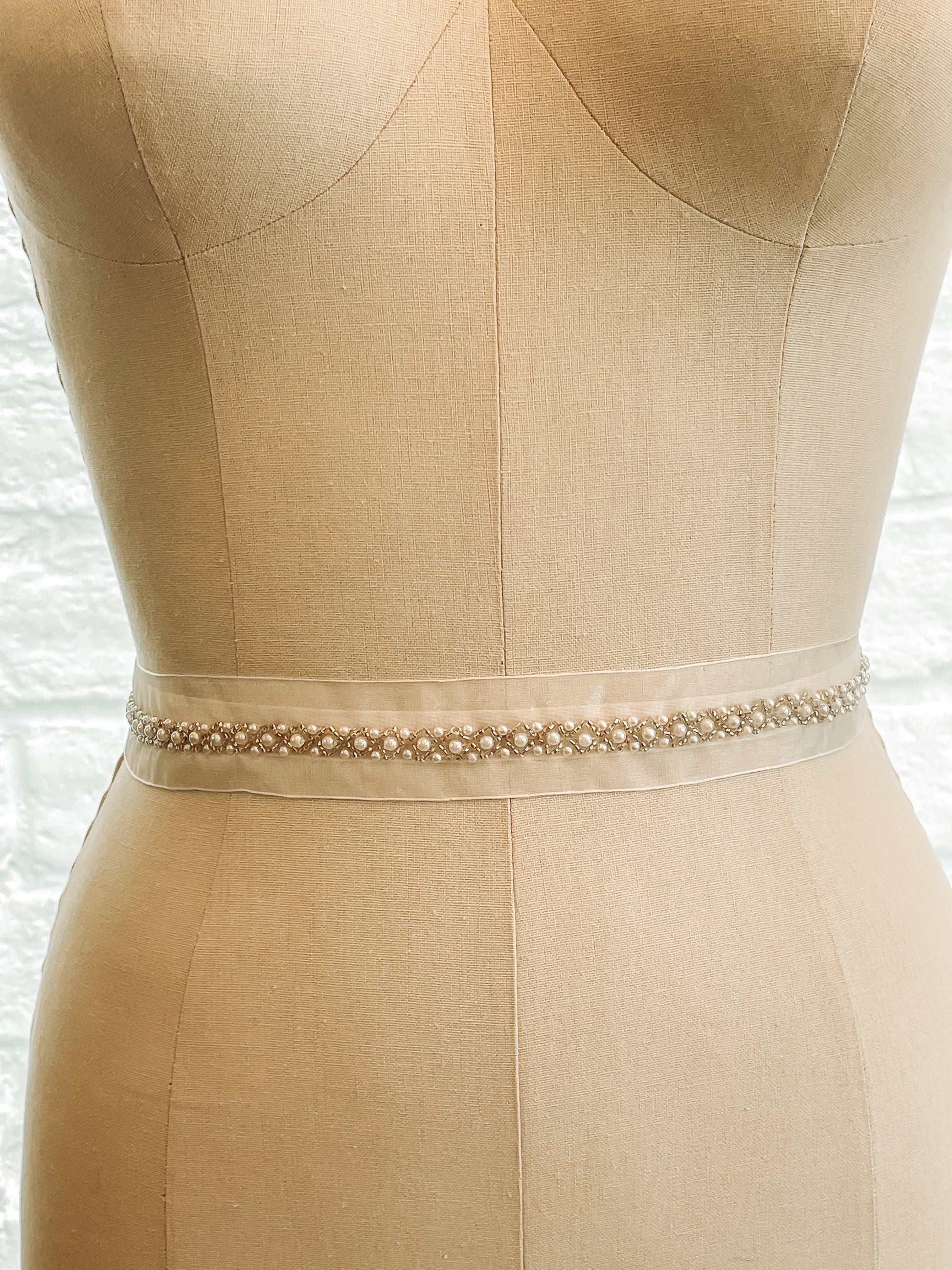 Close-up of silver and pearl diamond pattern on sheer organza of the fleur belt on a mannequin.