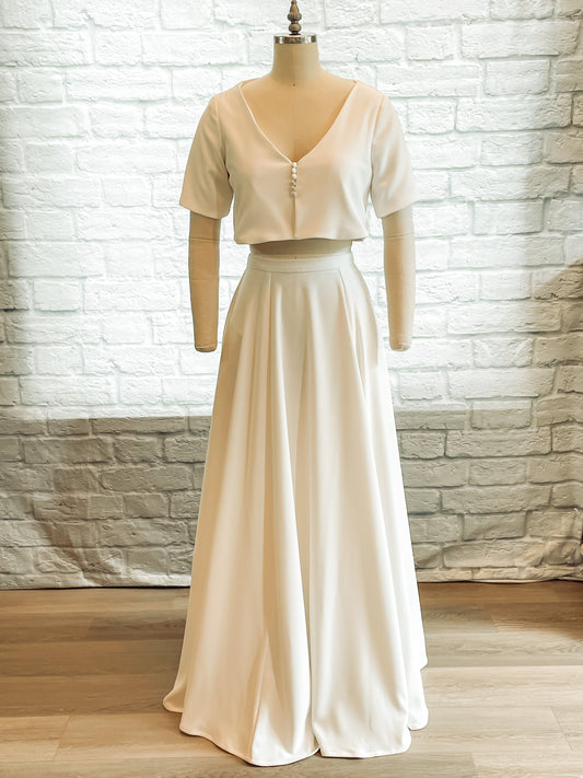 Front view of the Cassie two-piece wedding set on a mannequin, featuring a soft A-line stretch crepe skirt and cropped V-neck top with short sleeves and front buttons.