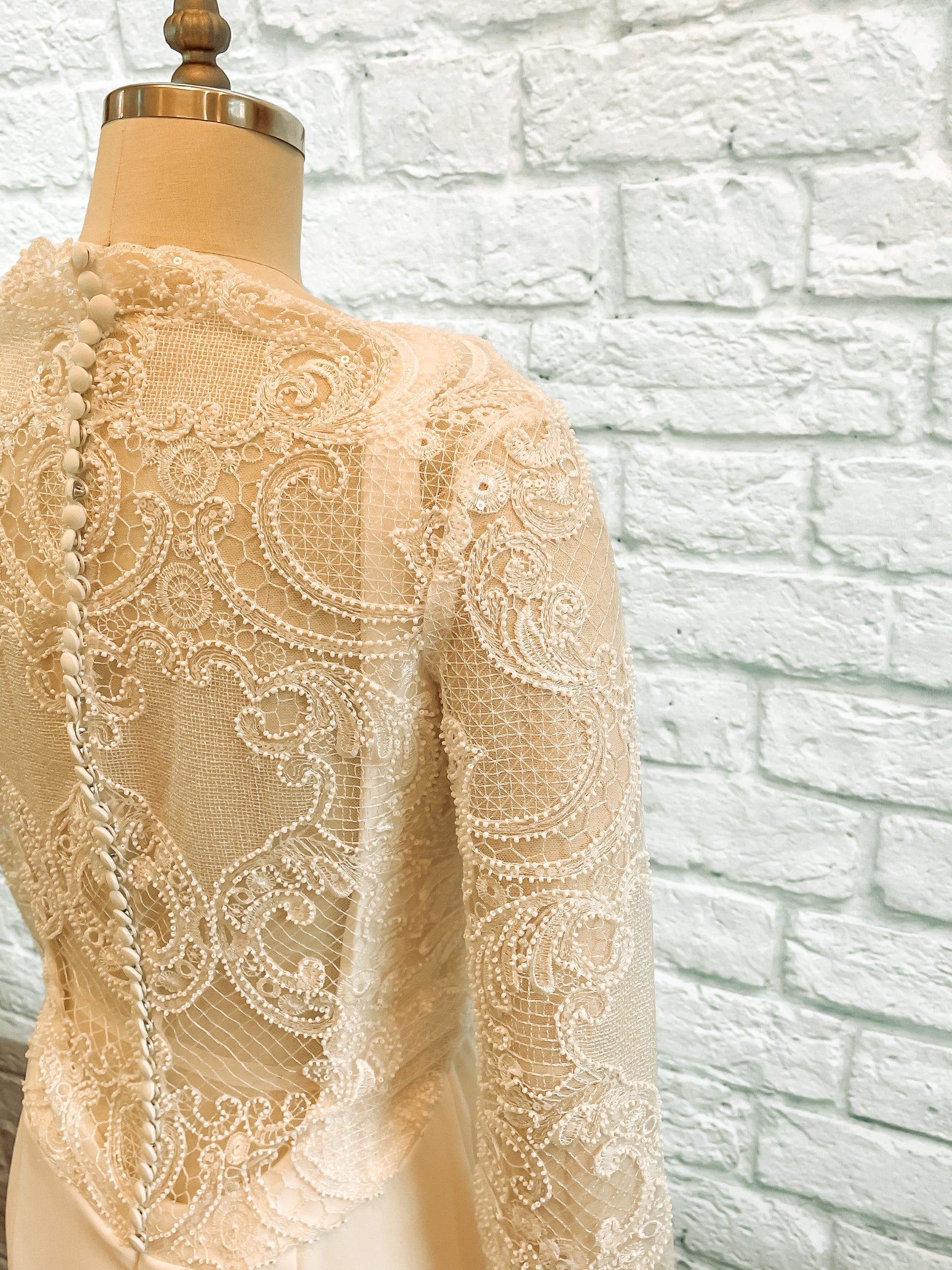 A detailed shot of the lace pattern on the zuri gowns sleeves and back bodice.