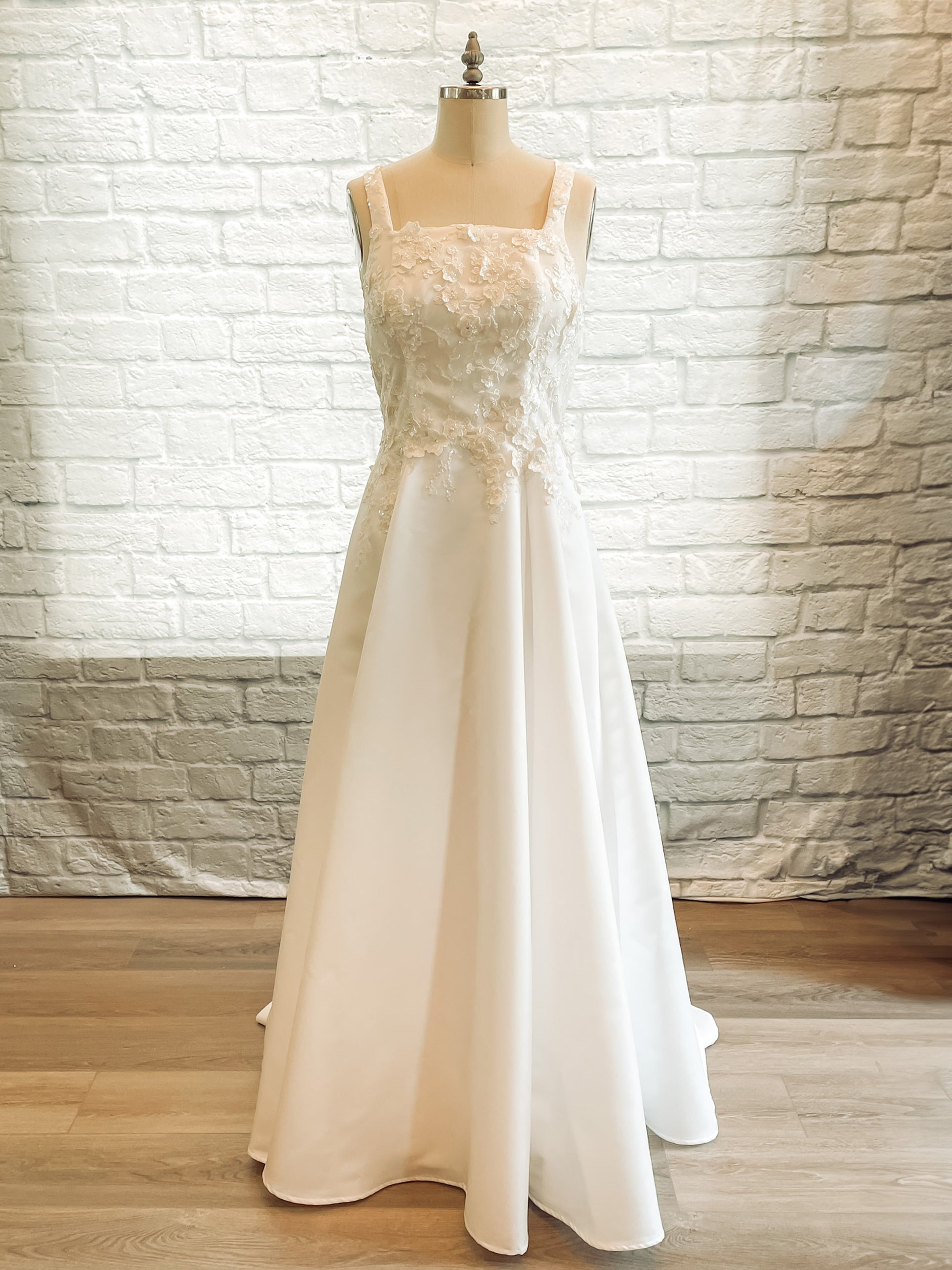 The sabina wedding gown is on a mannequin; the Sabina gown with square neckline, 1" wide straps, and lace bodice.