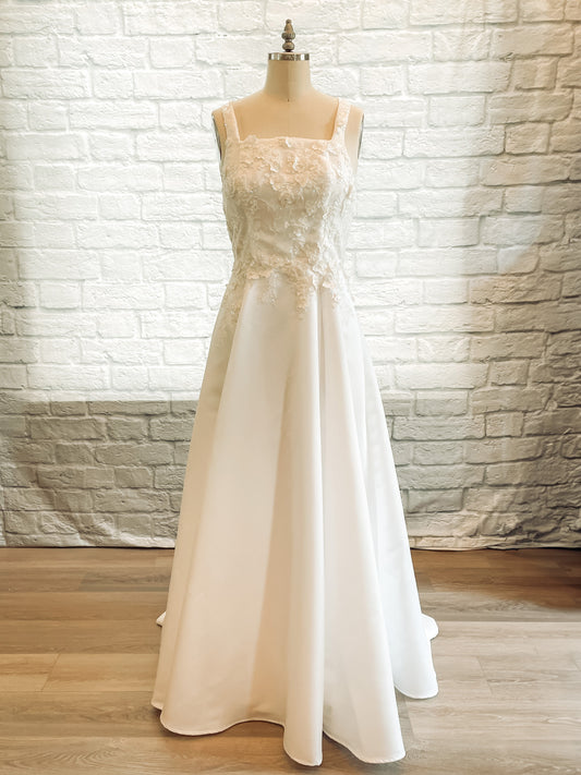 The sabina wedding gown is on a mannequin; the Sabina gown with square neckline, 1" wide straps, and lace bodice.