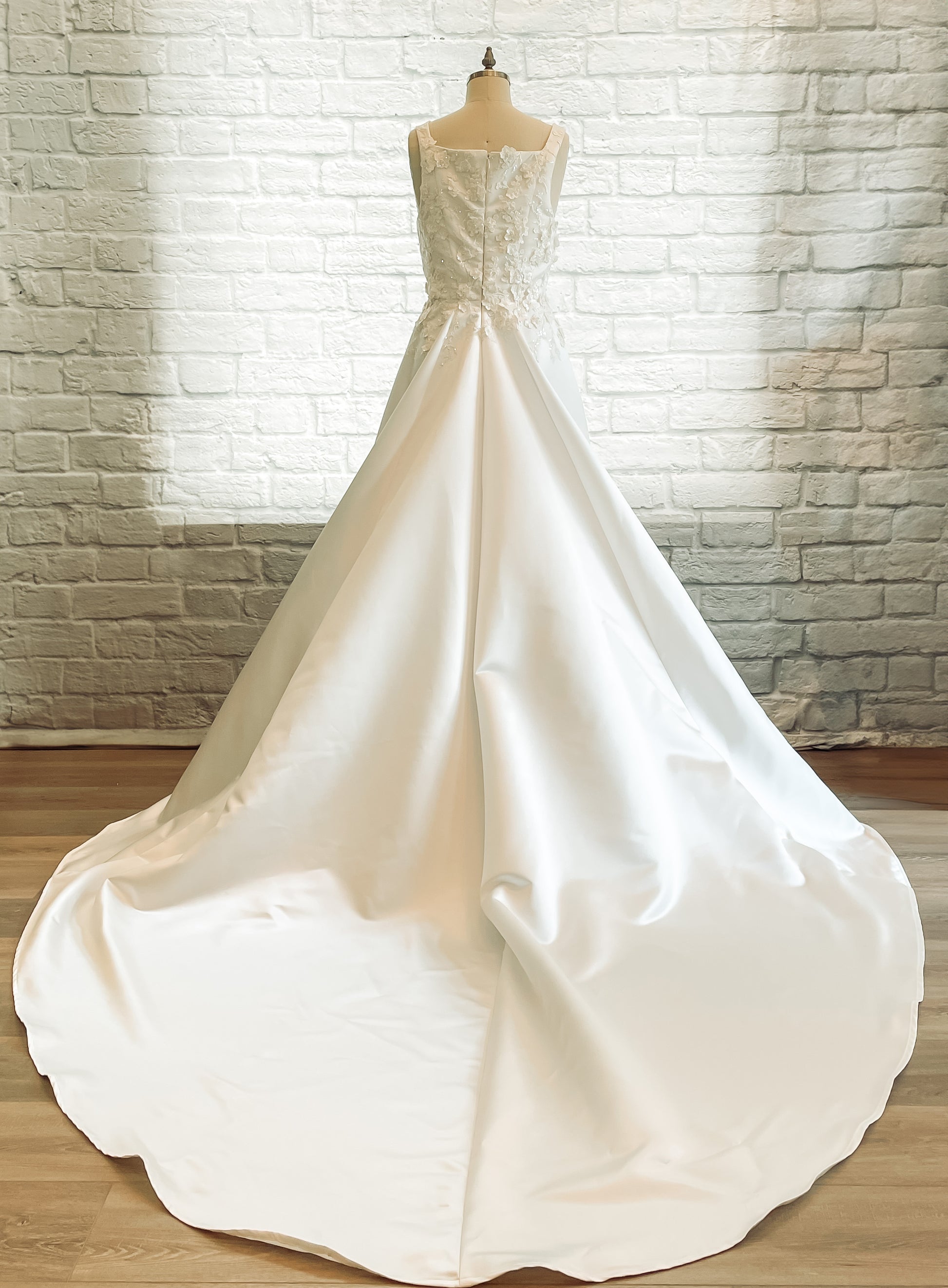 The Sabina gown is on a mannequin; showing the full back it has a square back neckline and extra-long duchess satin train.