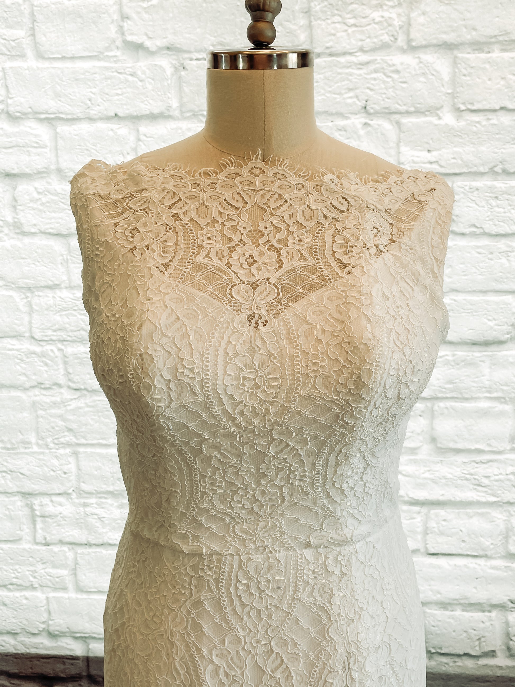 Close-up of the front bodice on the Blair gown, featuring the scalloped lace neckline edge and floral motifs of the wide boat neck.