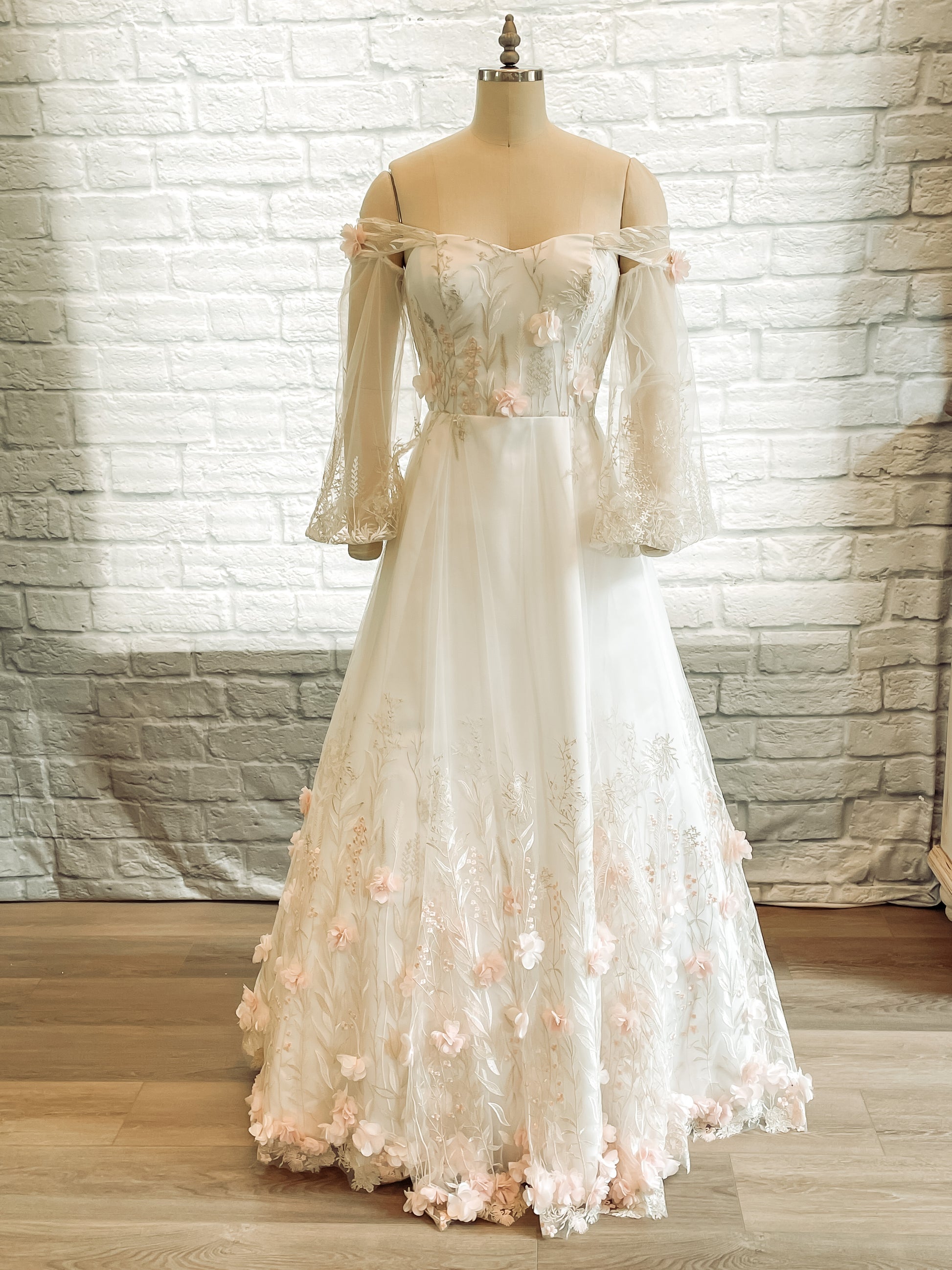 Full front view of the Prue wedding dress on a mannequin with sweetheart neckline, bishop sleeves, and 3D floral lace.