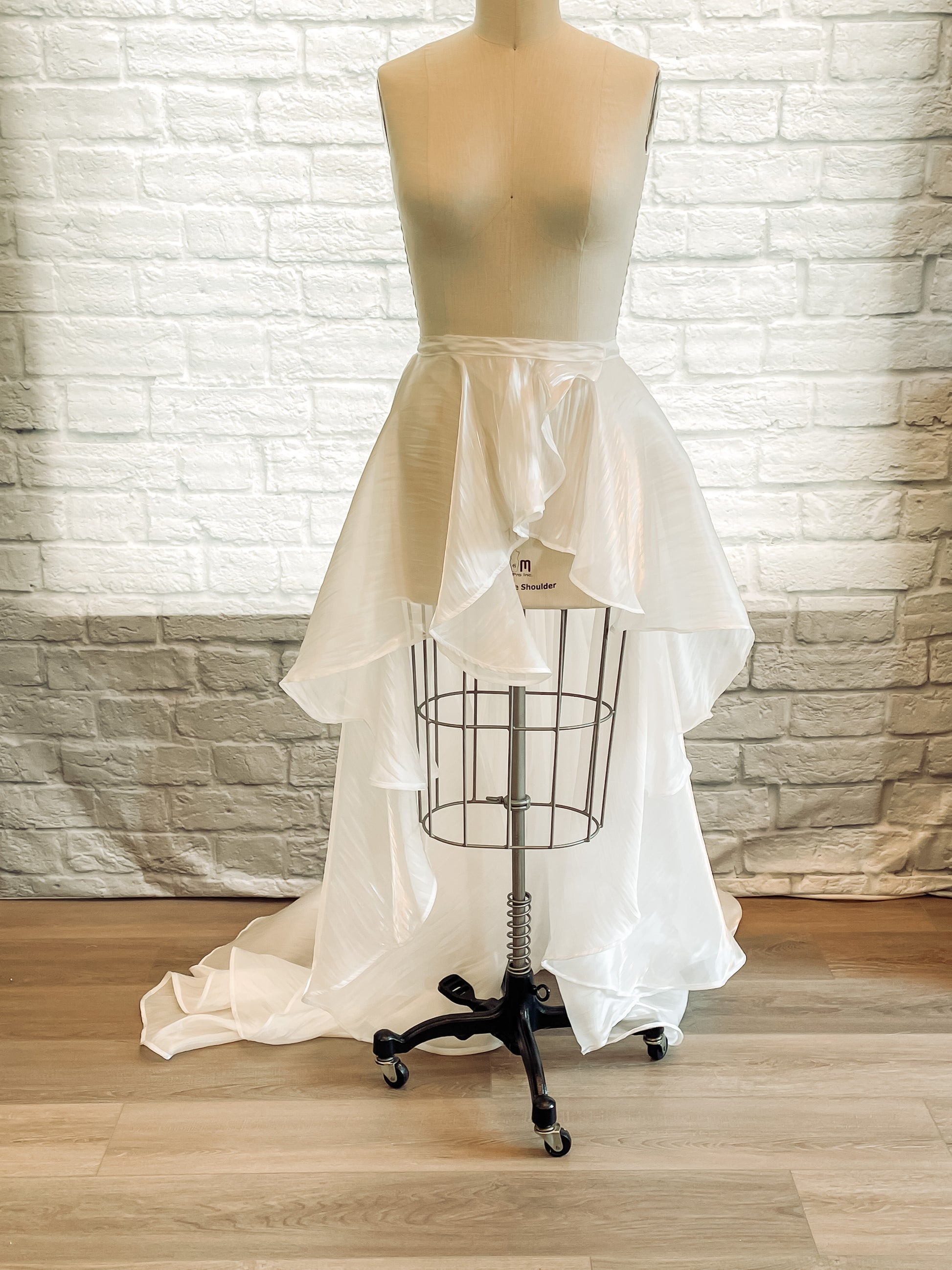 Full-length view of a mannequin wearing the Amber removable organza skirt, showing cascading ruffles and a soft train