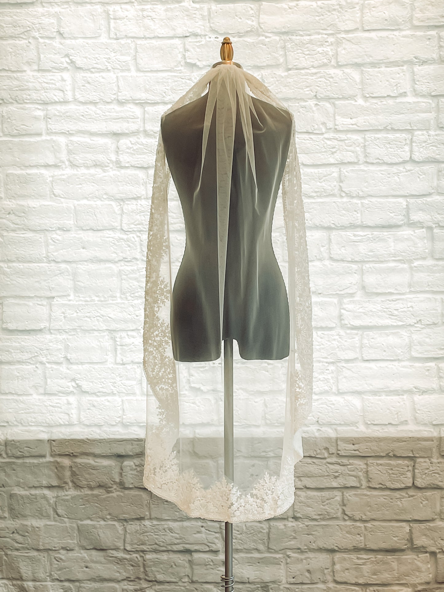 A photo of the Ireland veil with both edges pulled over the shoulders of a mannequin in a calf length.