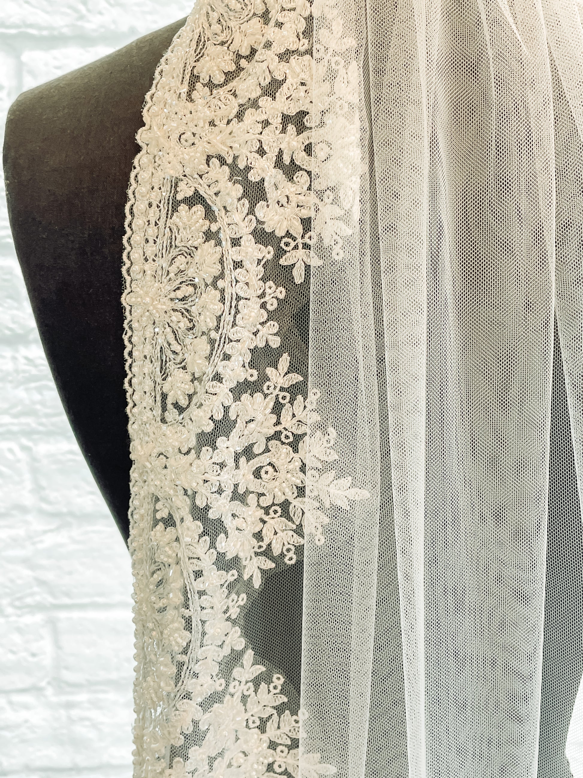 A close up of the edge of the Ireland veil with fan-shaped beading and mini scalloped edges sewn to a tulle base.