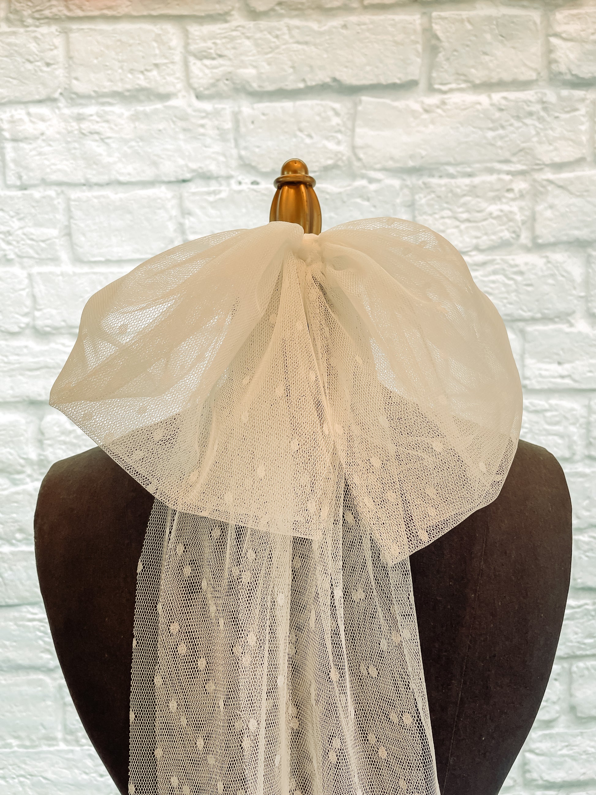 A close up of the bridal bow veil displayed on a mannequin in swiss dot fabric.
