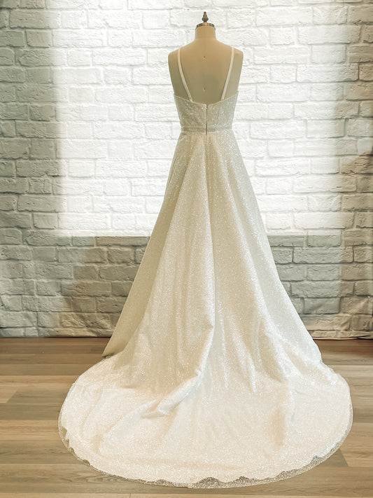 Back view showing the gentle scoop and the glitter fabric cascading into a train