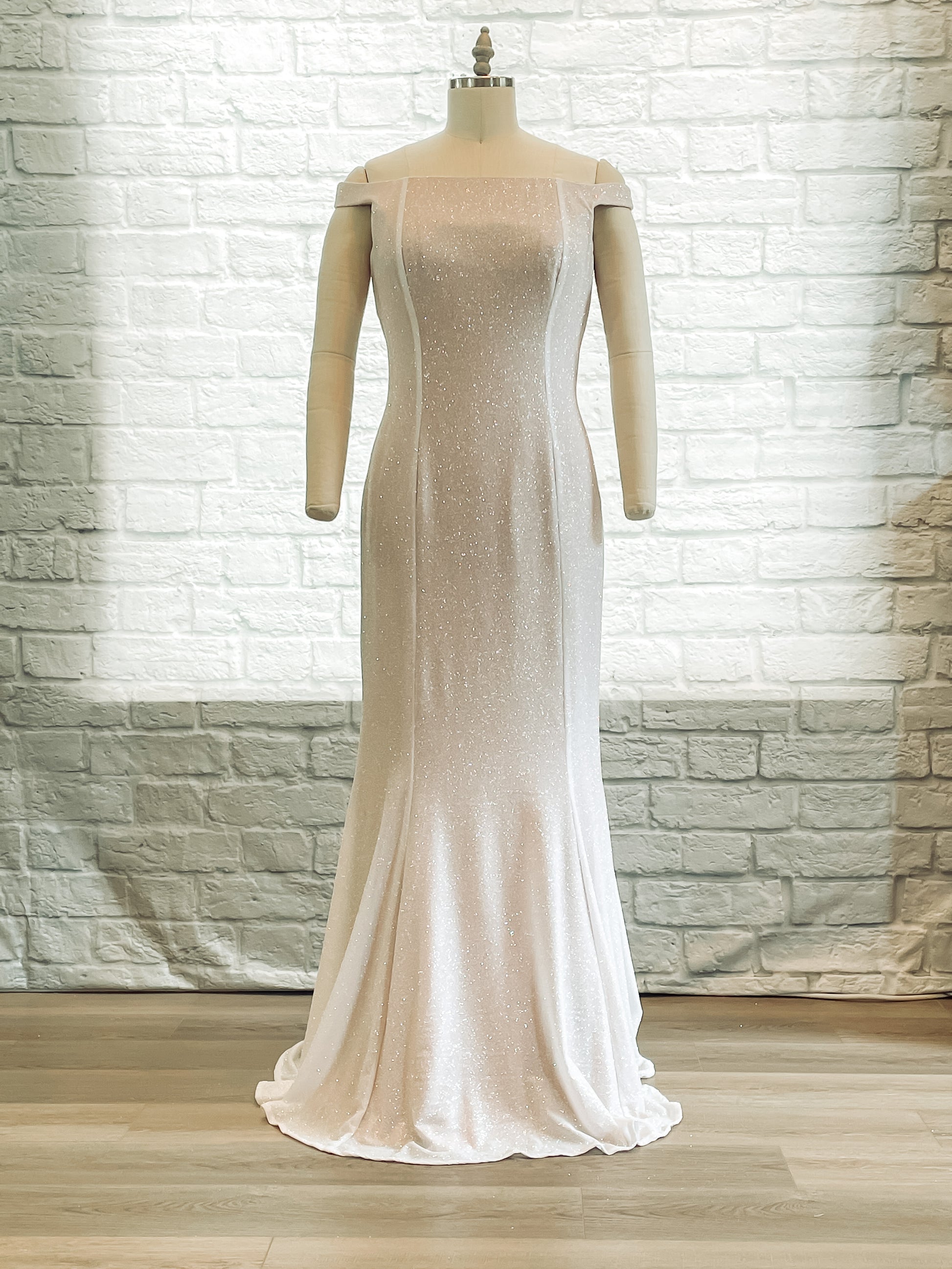 Front view of the Alora off-the-shoulder glitter trumpet wedding gown on a mannequin with an off the shoulder cut.