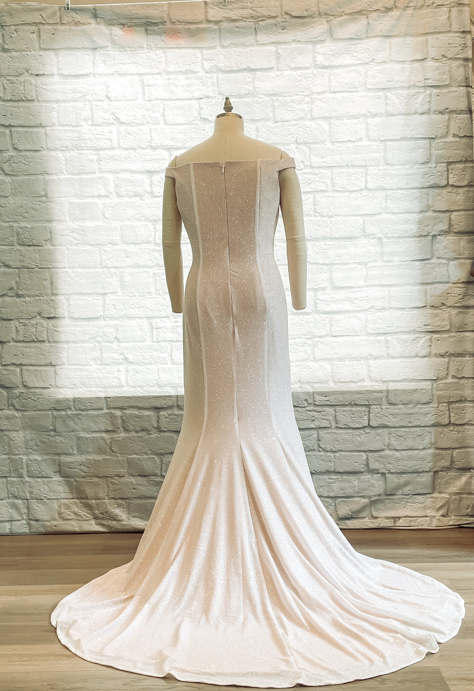 Back view of a mannequin  wearing the Alora dress highlighting curve-hugging trumpet silhouette and long train