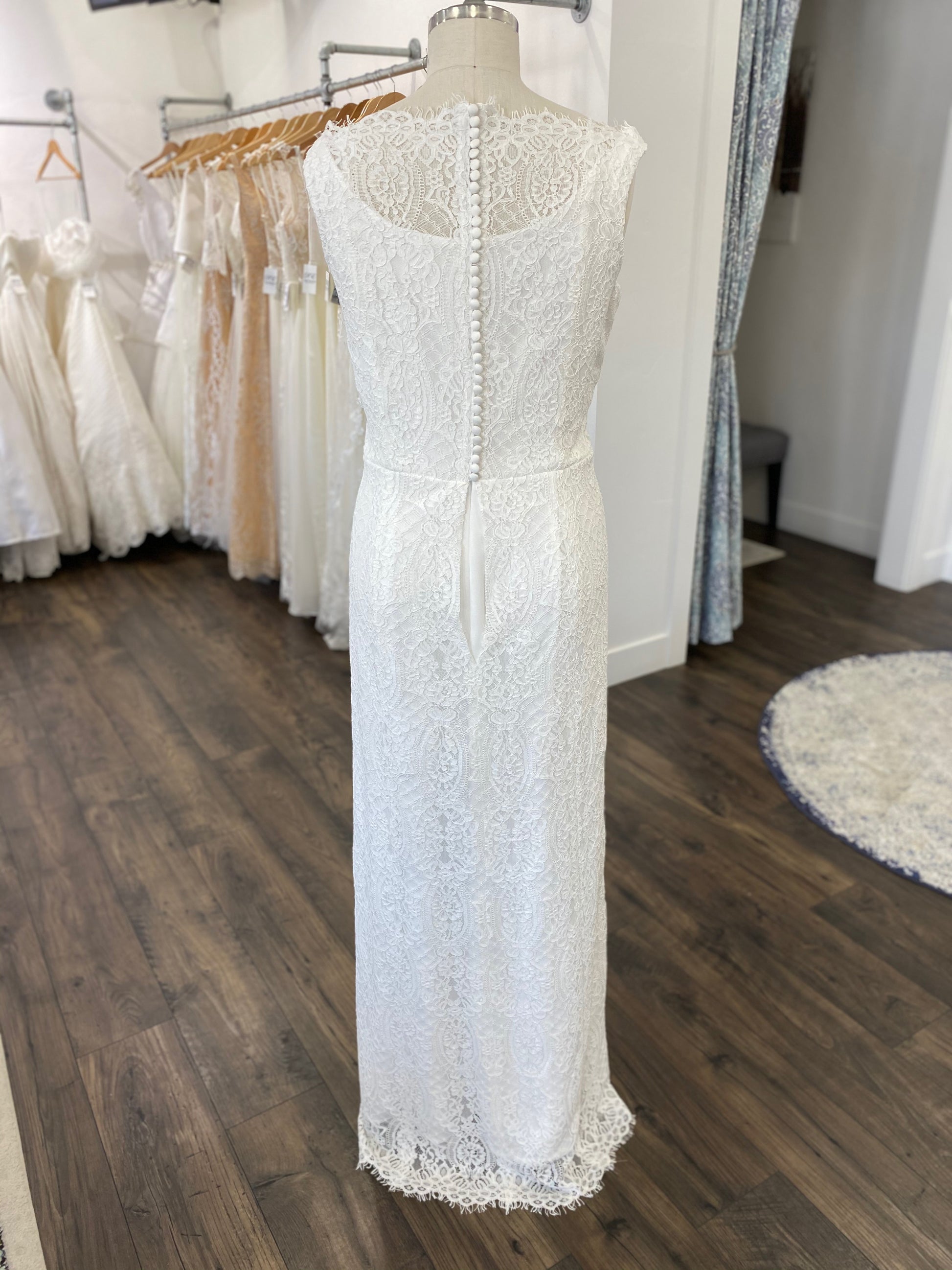 Mannequin wearing the Blair gown in a brightly lit studio, emphasizing the timeless and graceful lace overlay from top to hem