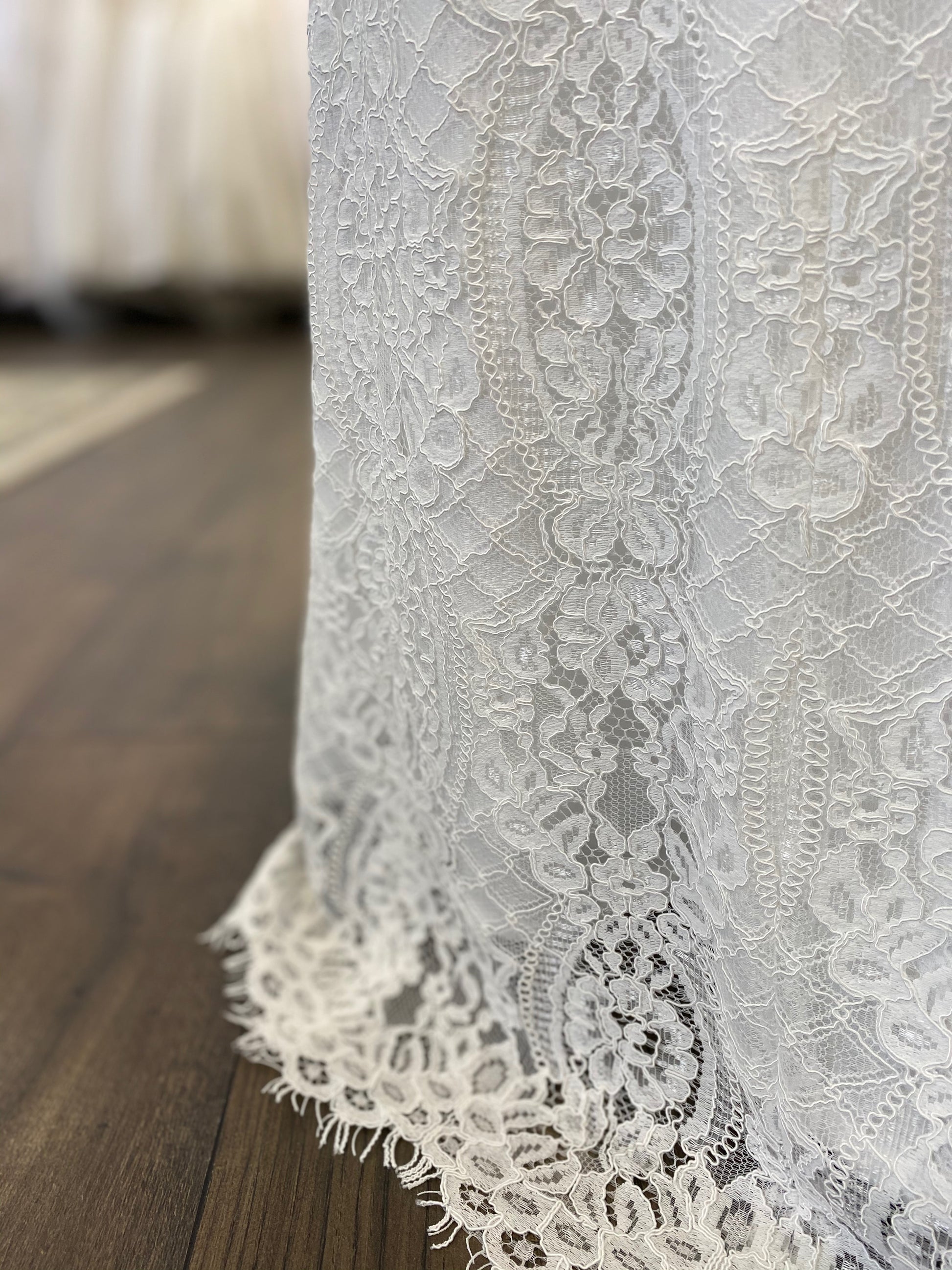 Close-up of the hemline of the Blair gown on a mannequin, highlighting the scalloped lace with delicate eyelash edging.
