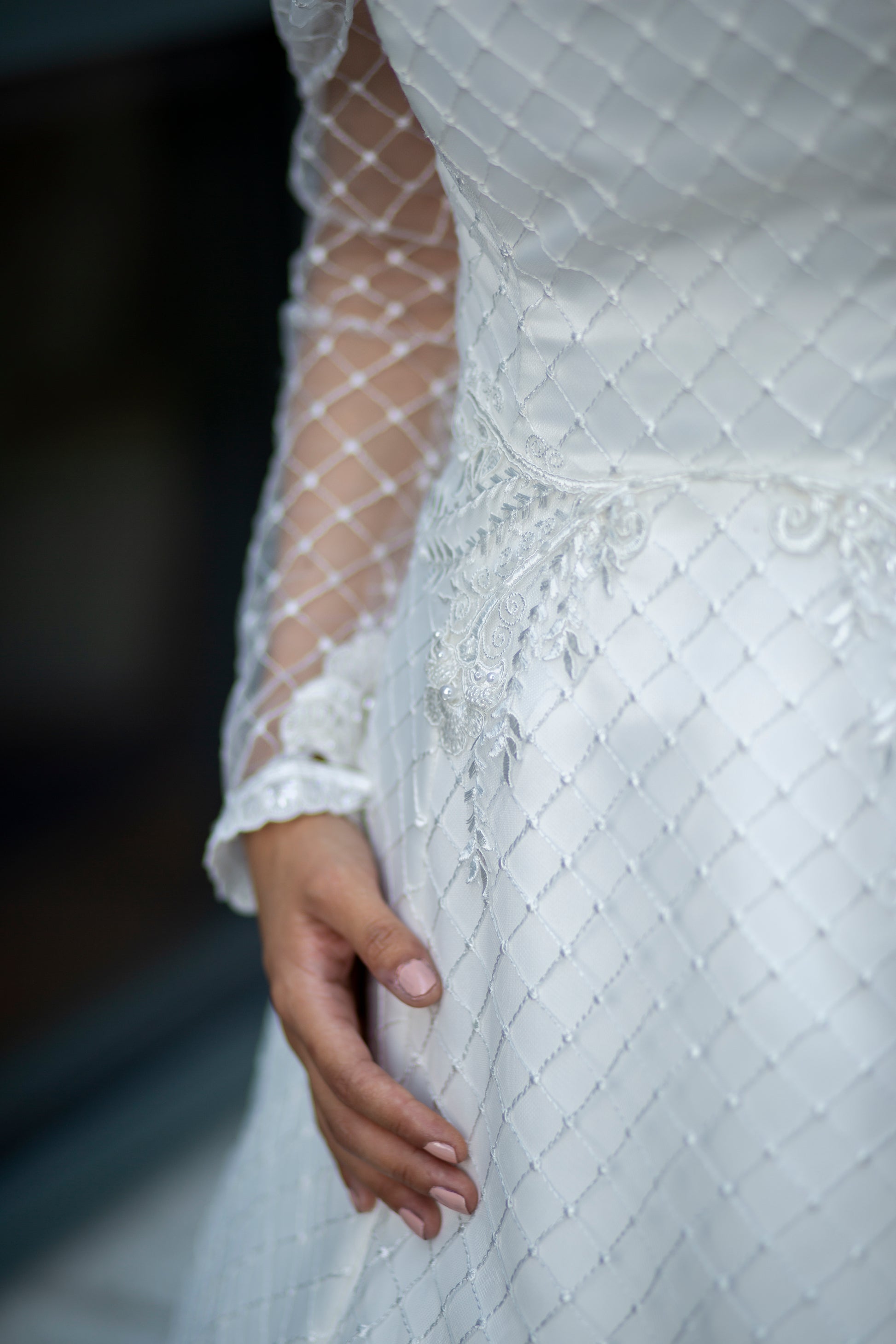 A close up of the diamond tulle that covers the bodice, sleeve and top of the skirt on the Virginia gown. Along the wasit seam   there is hand placed lace that swirls around the seam   and down into the skirt.