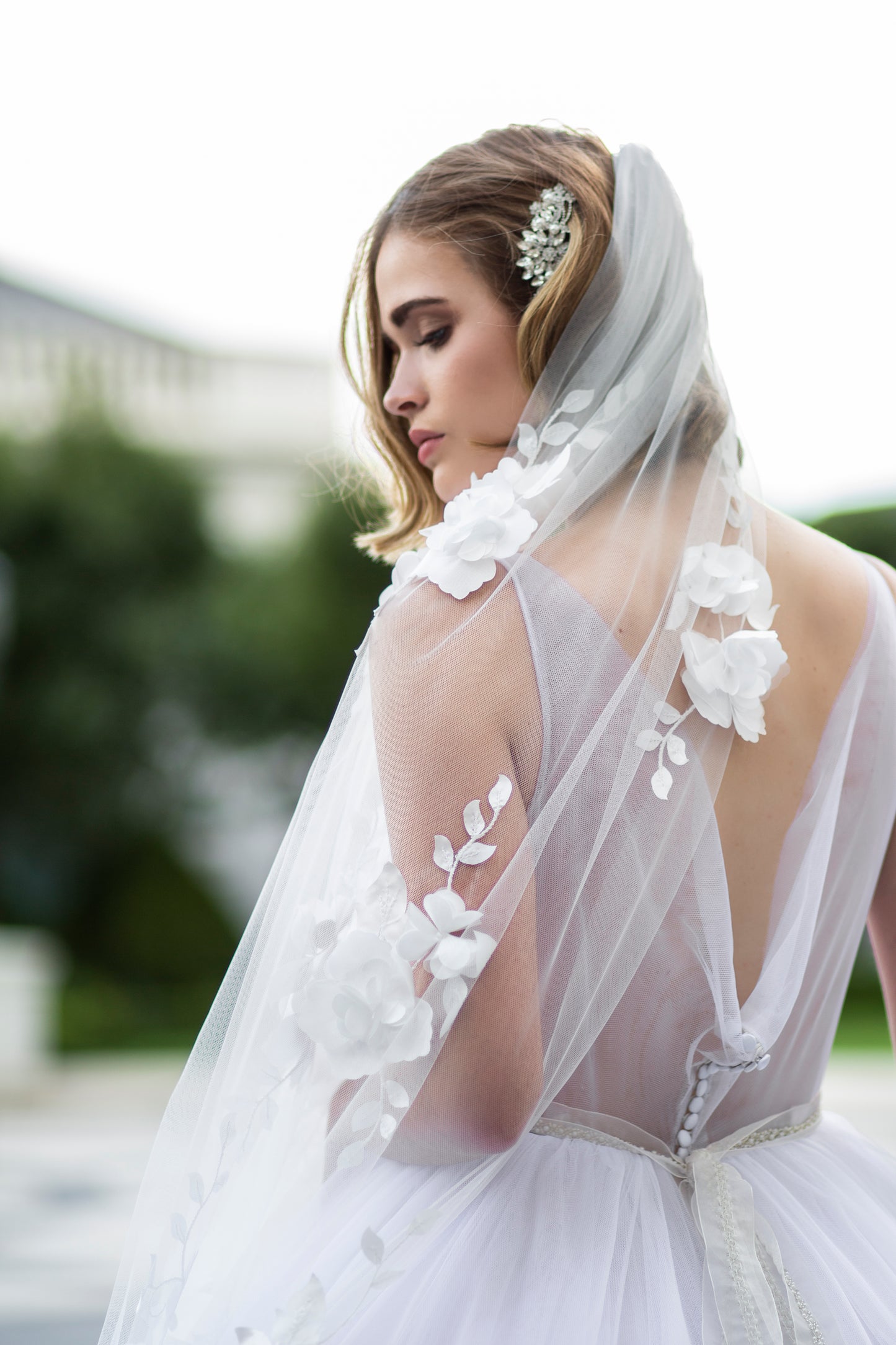 This photo shows a bride wearing our perephone gown, fleur belt and the celine veil. The veil is the foal point and shows cascading flower accents that come off the veil with a 3d effect.
